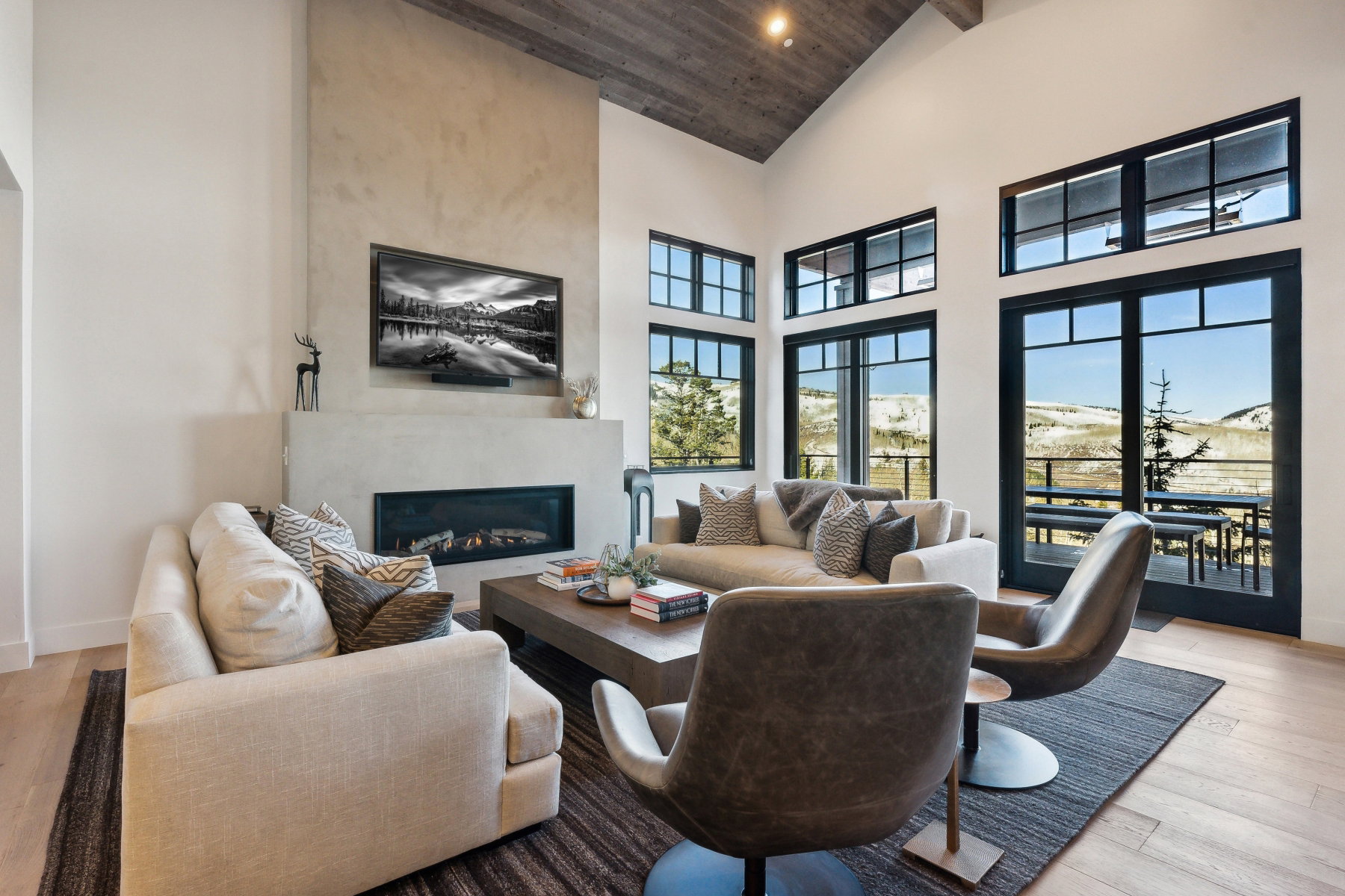 Spacious living area featuring a vaulted wood-finish ceiling, light wood-finish flooring, and a contemporary fireplace with a wide hearth