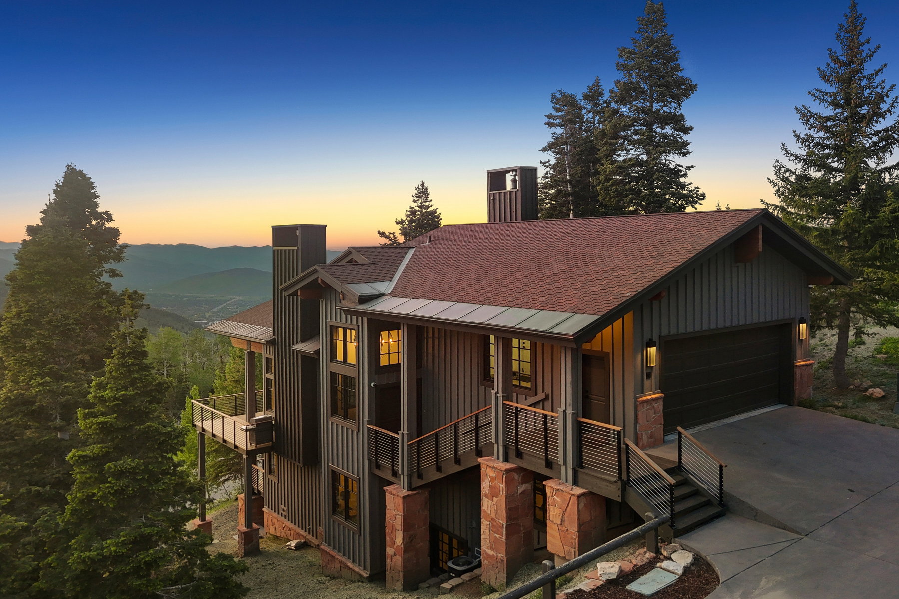 Contemporary-style residence featuring a dark wood-paneled exterior, a two-car garage with a dark door, and a prominent balcony