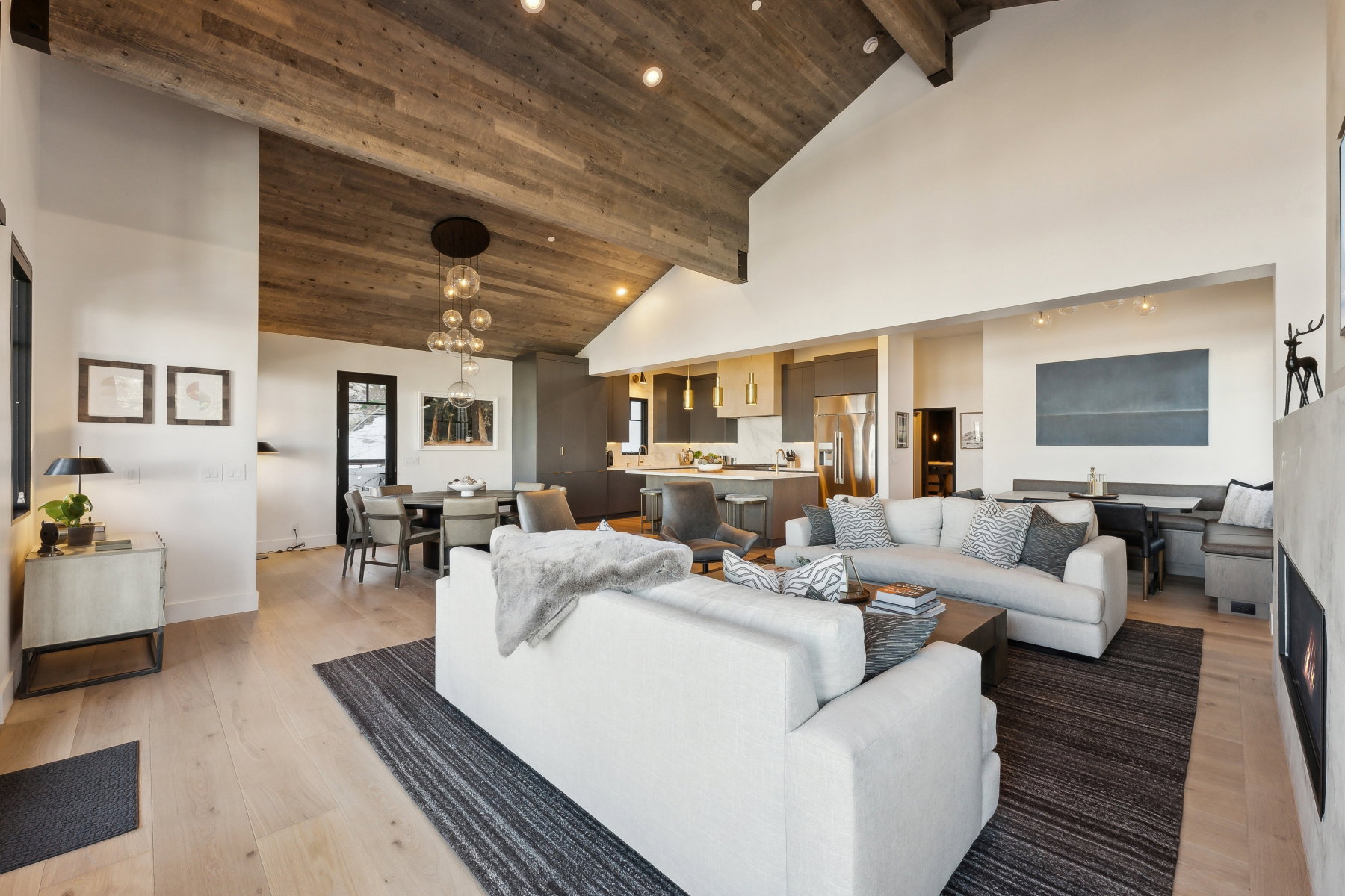 Spacious open-concept living area featuring wood-finish flooring, a vaulted wood-paneled ceiling, and a built-in fireplace