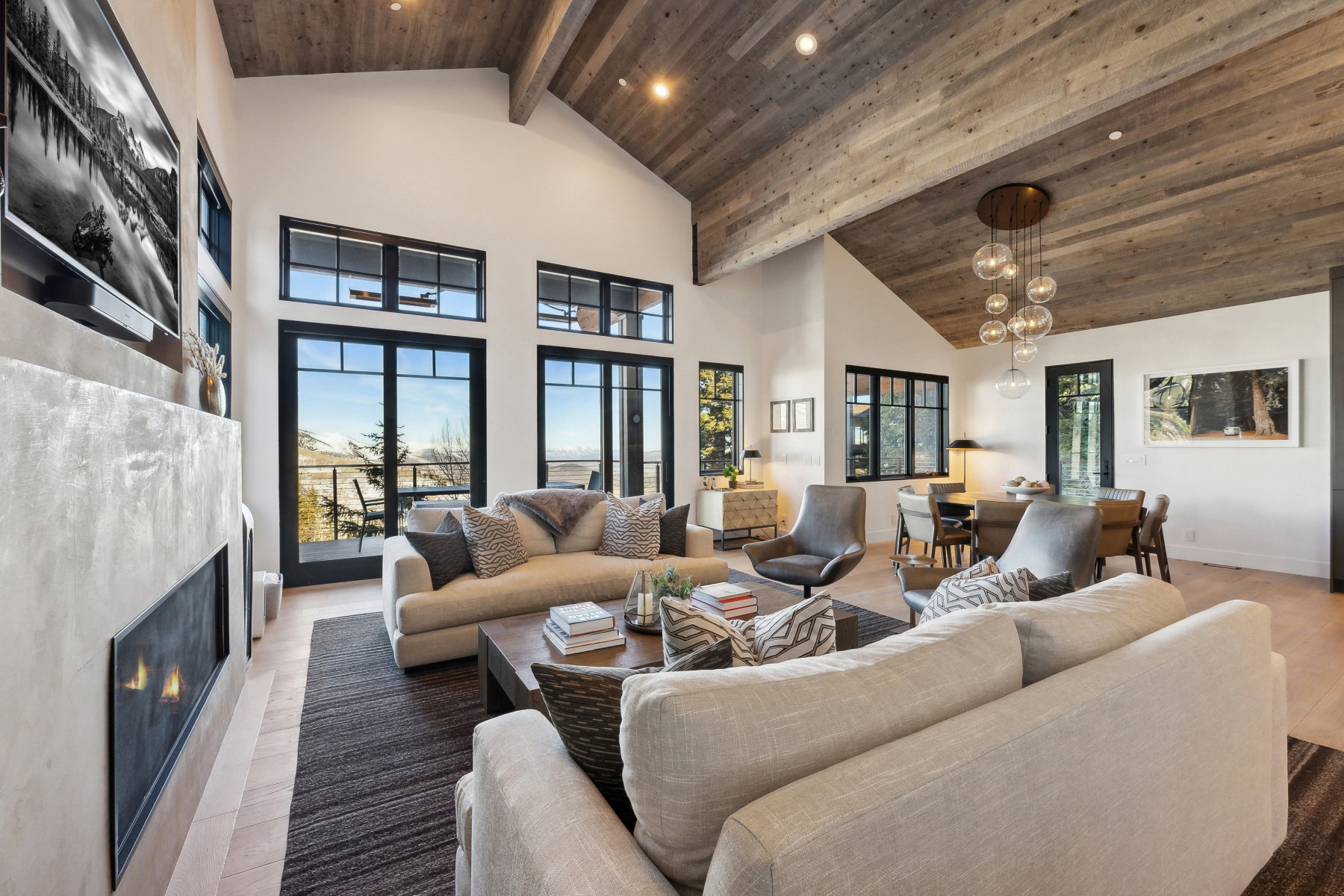 Vaulted wood-paneled ceilings with exposed beams define this spacious living area, featuring a linear fireplace with a textured surround