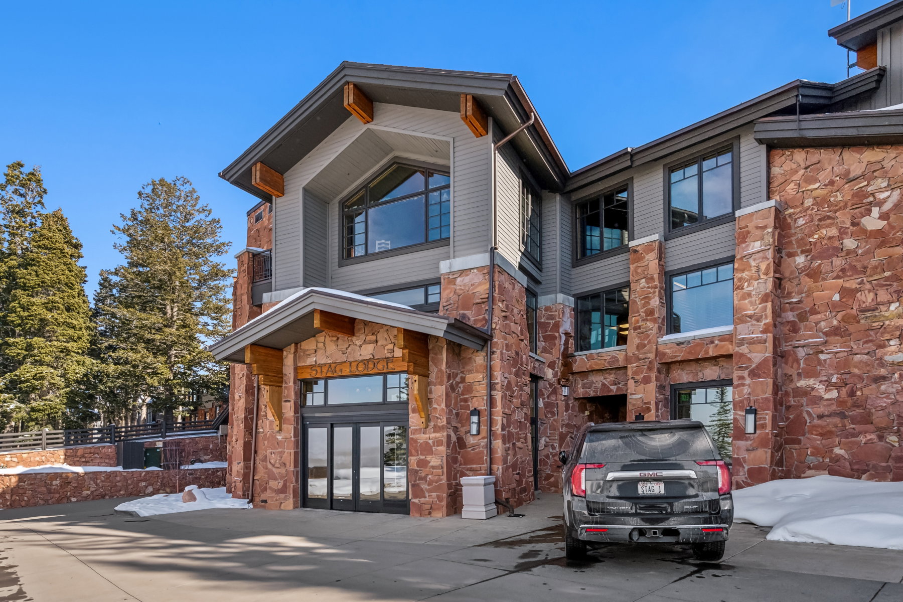 Stone and siding exterior construction featuring large format windows, a prominent gable, and a covered entry