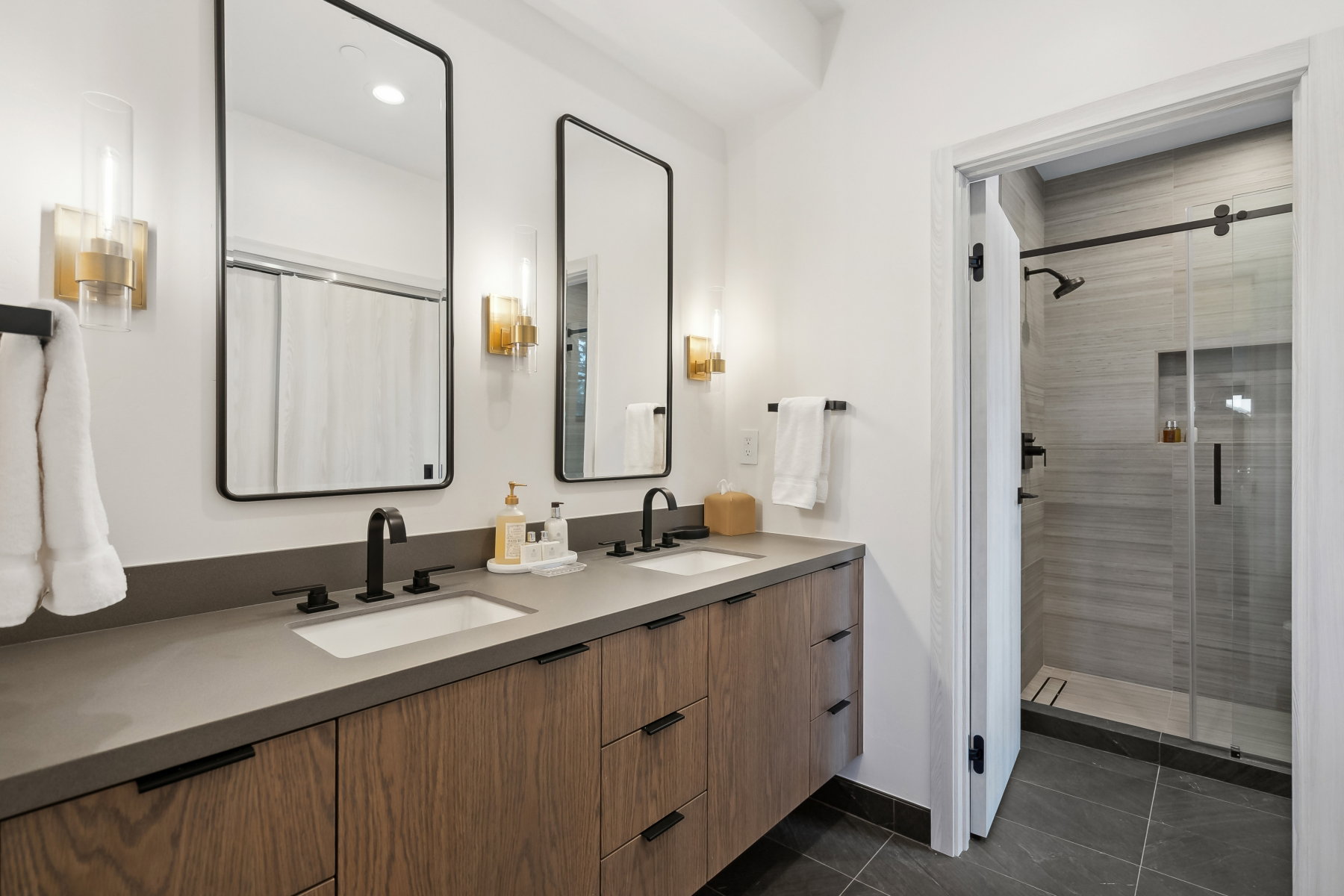 Double vanity featuring wood-finish cabinetry, integrated rectangular sinks, and matte black fixtures
