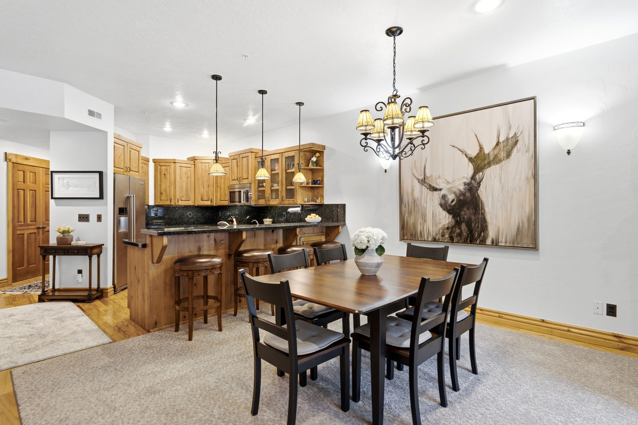 Open-concept dining area featuring a dark wood dining table with seating for six, illuminated by a decorative chandelier