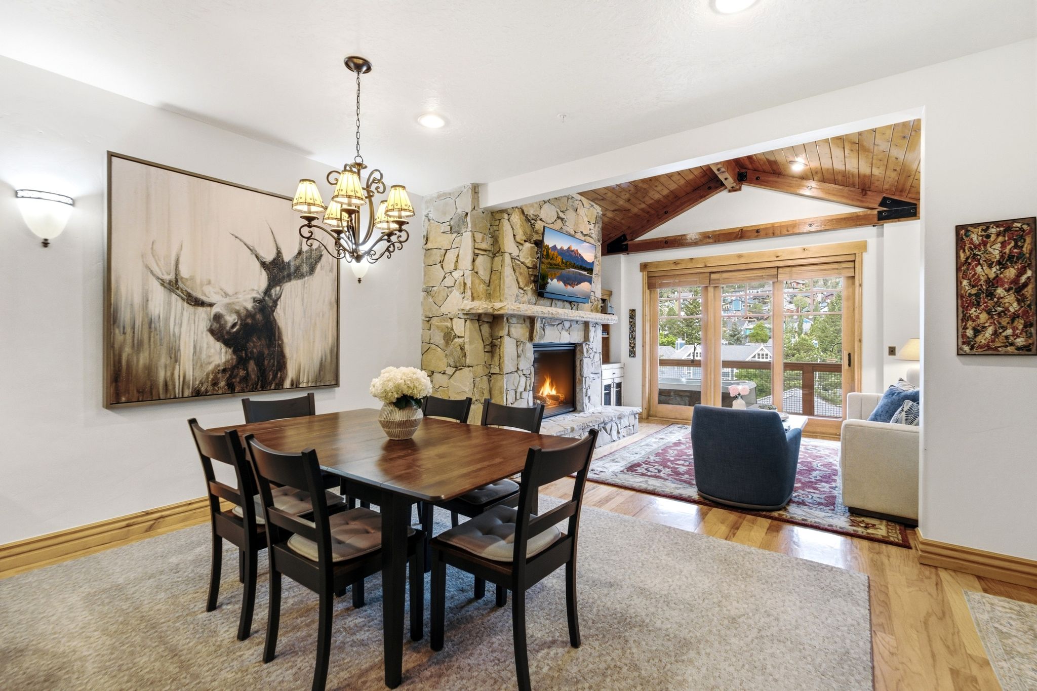 Open-concept dining area featuring a dark wood dining table with seating for six, illuminated by a decorative chandelier