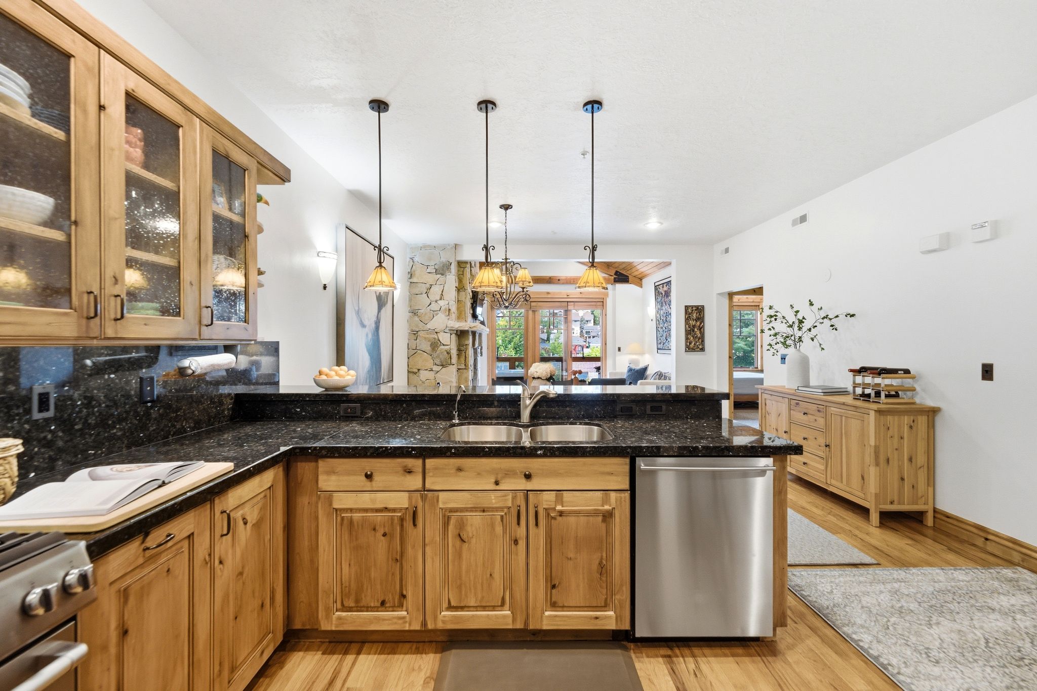 Open-concept kitchen and dining area featuring light wood cabinetry, granite, stainless steel appliances, and wood flooring