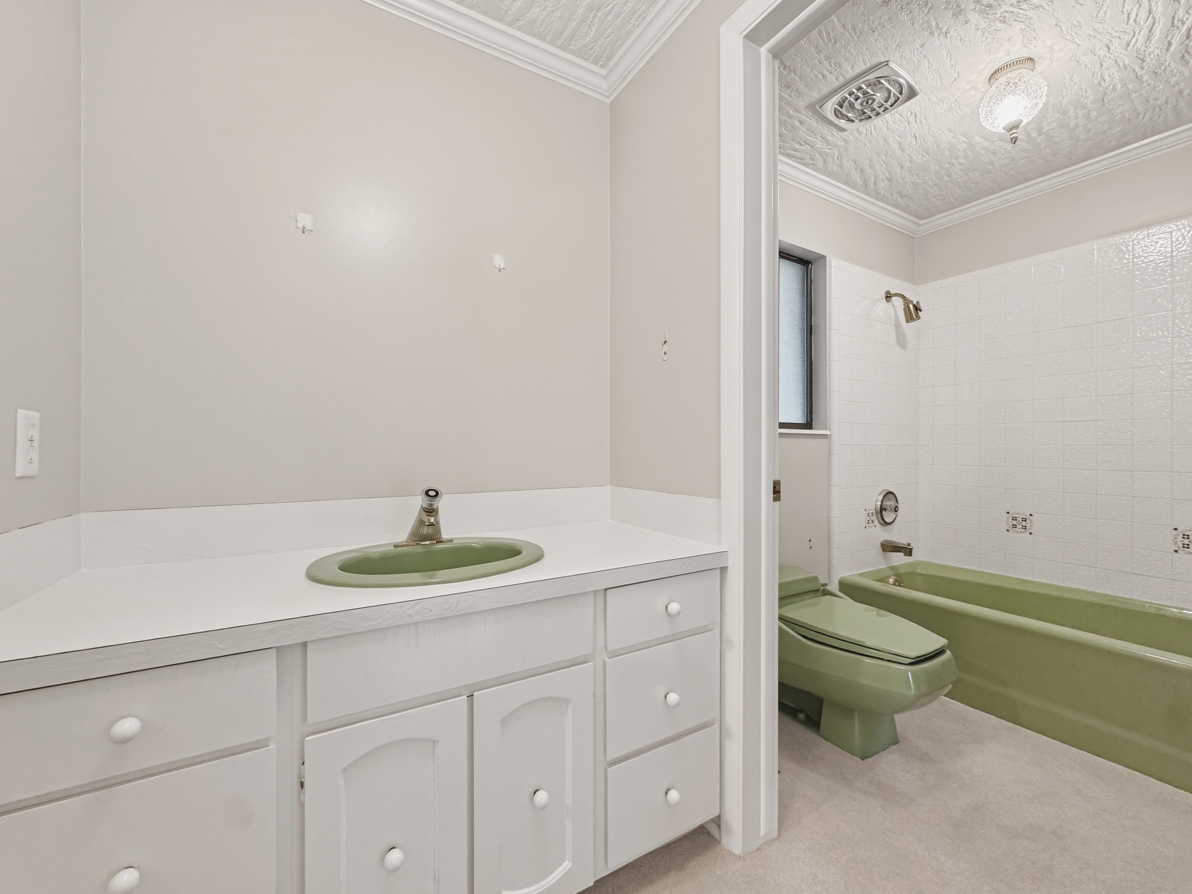 Bathroom featuring a white vanity with an integrated green sink and white cabinetry