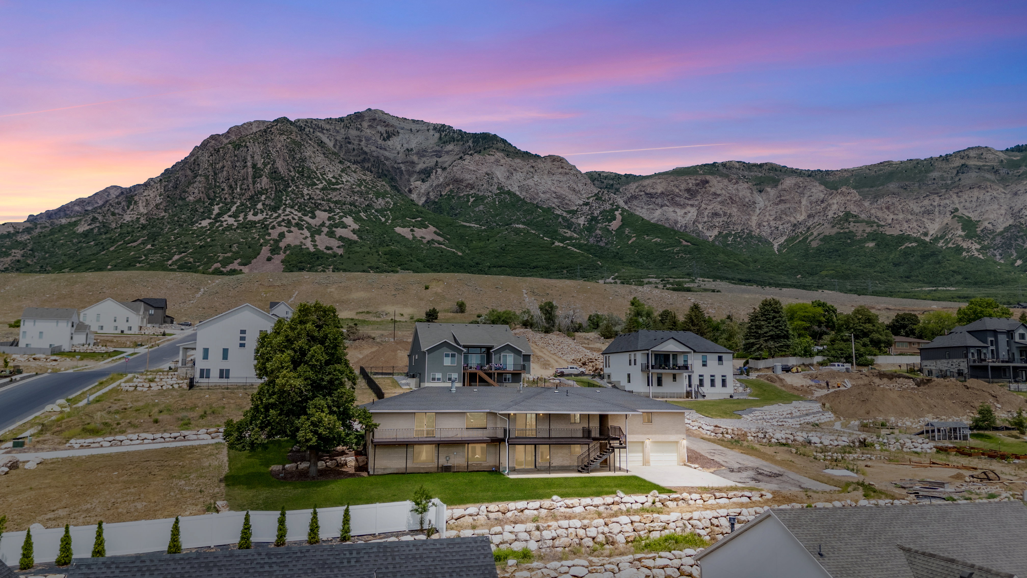 Multi-story residence featuring a two-car garage, upper and lower level balconies, and a mountain backdrop
