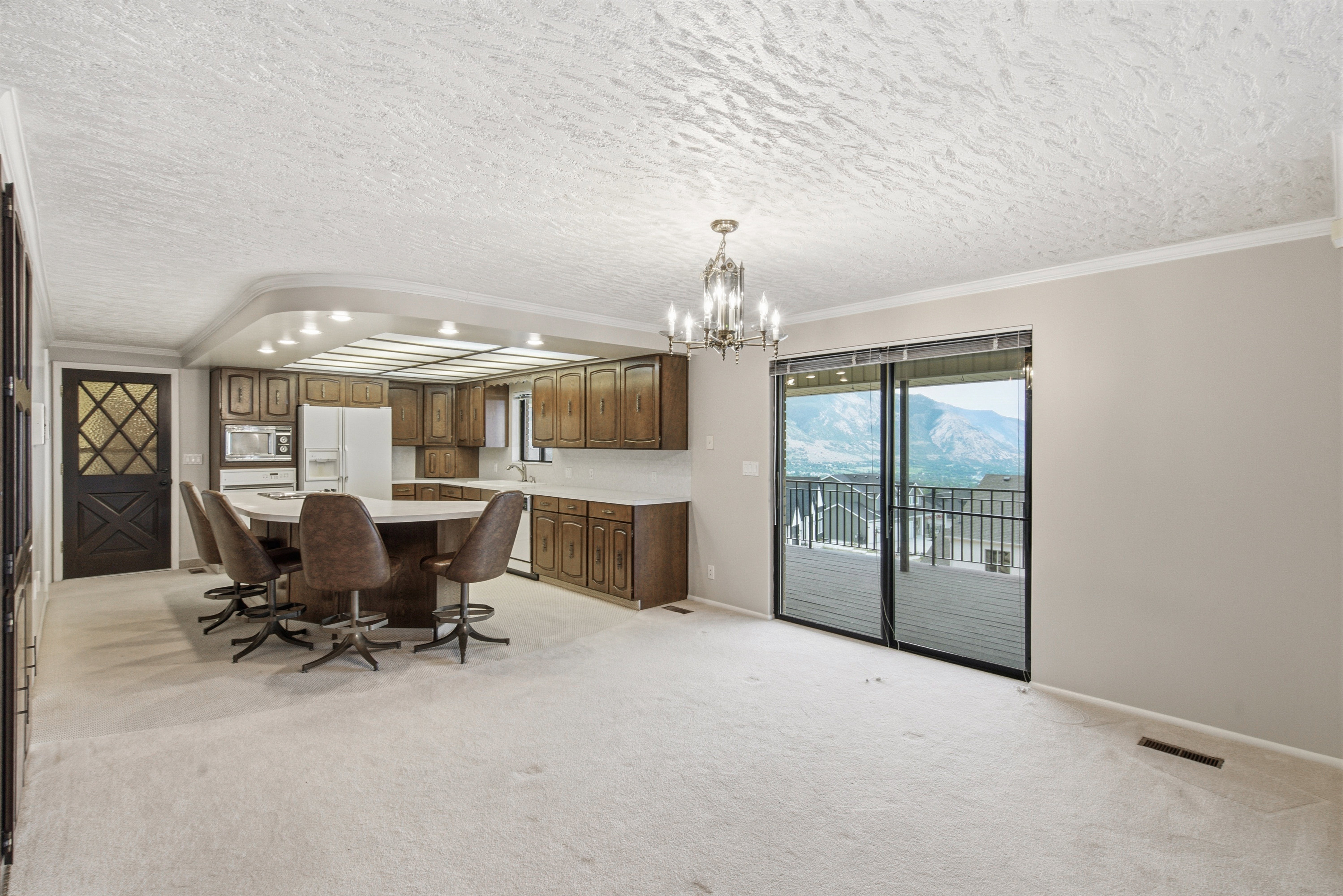 Open-concept kitchen and living area featuring a large center island with seating, wood-finish cabinetry, built-in appliances, and recessed lighting