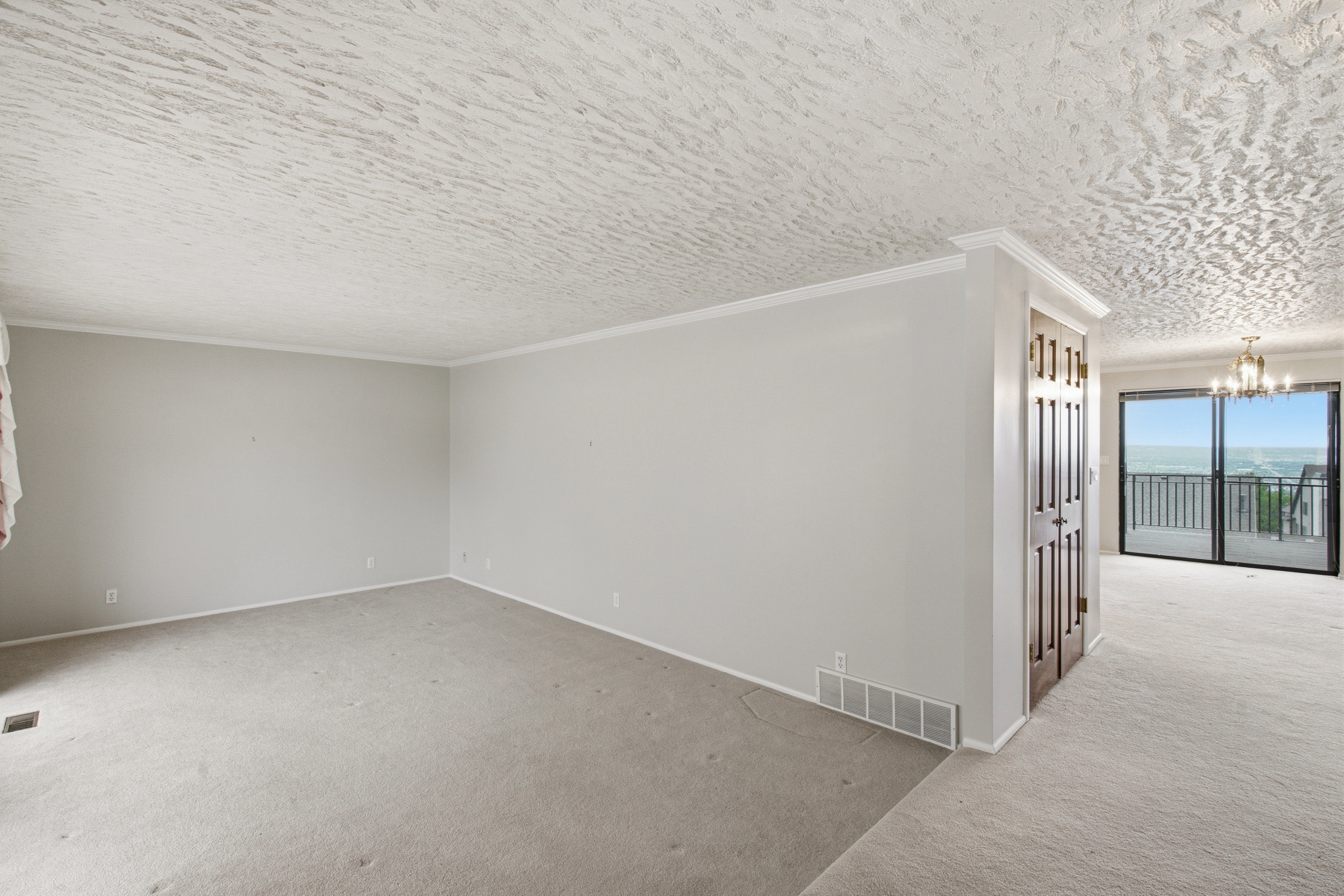 Light gray carpeted room featuring white crown molding and baseboards