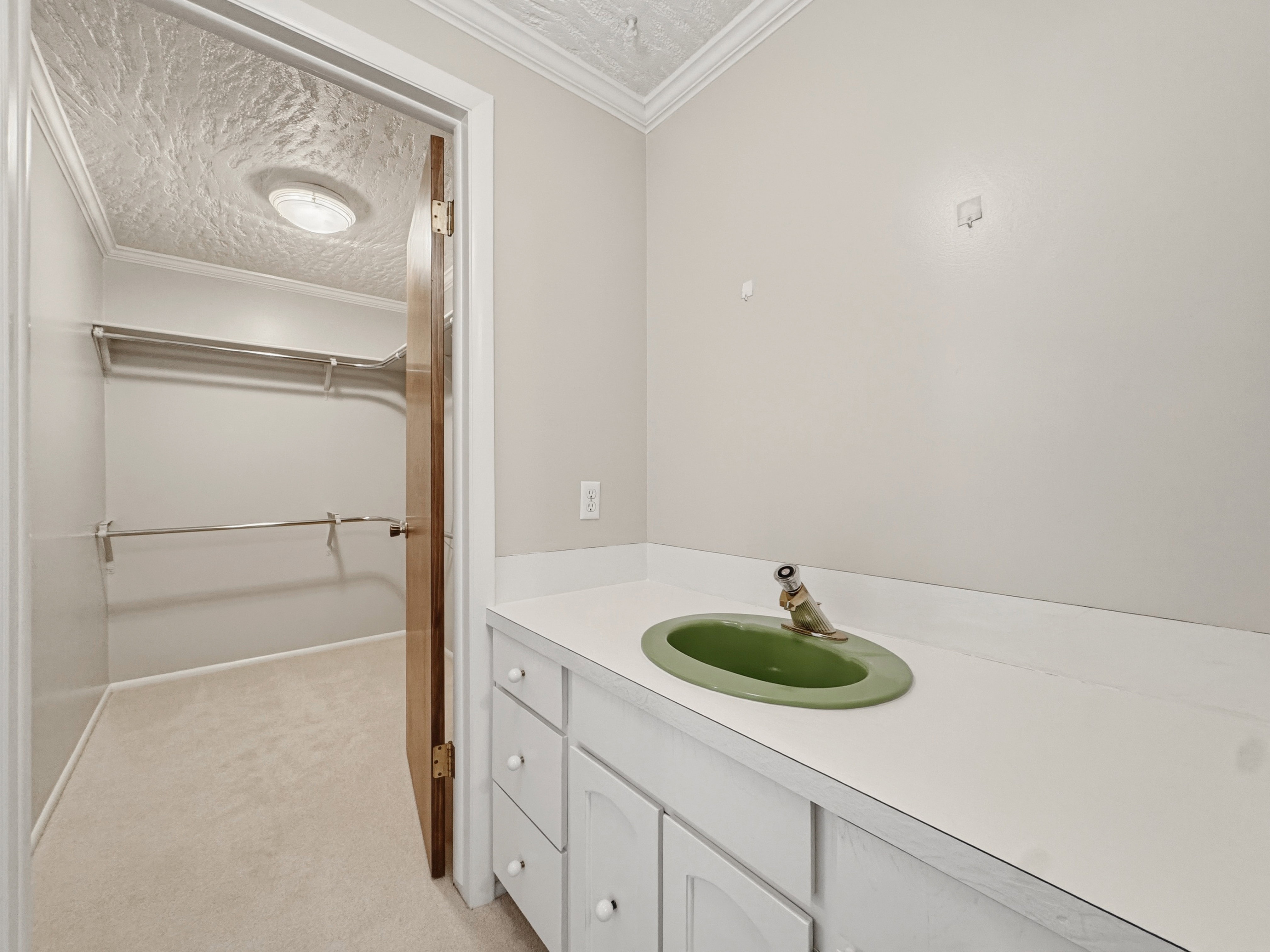 Vanity with an integrated green basin, white countertop, and white cabinetry