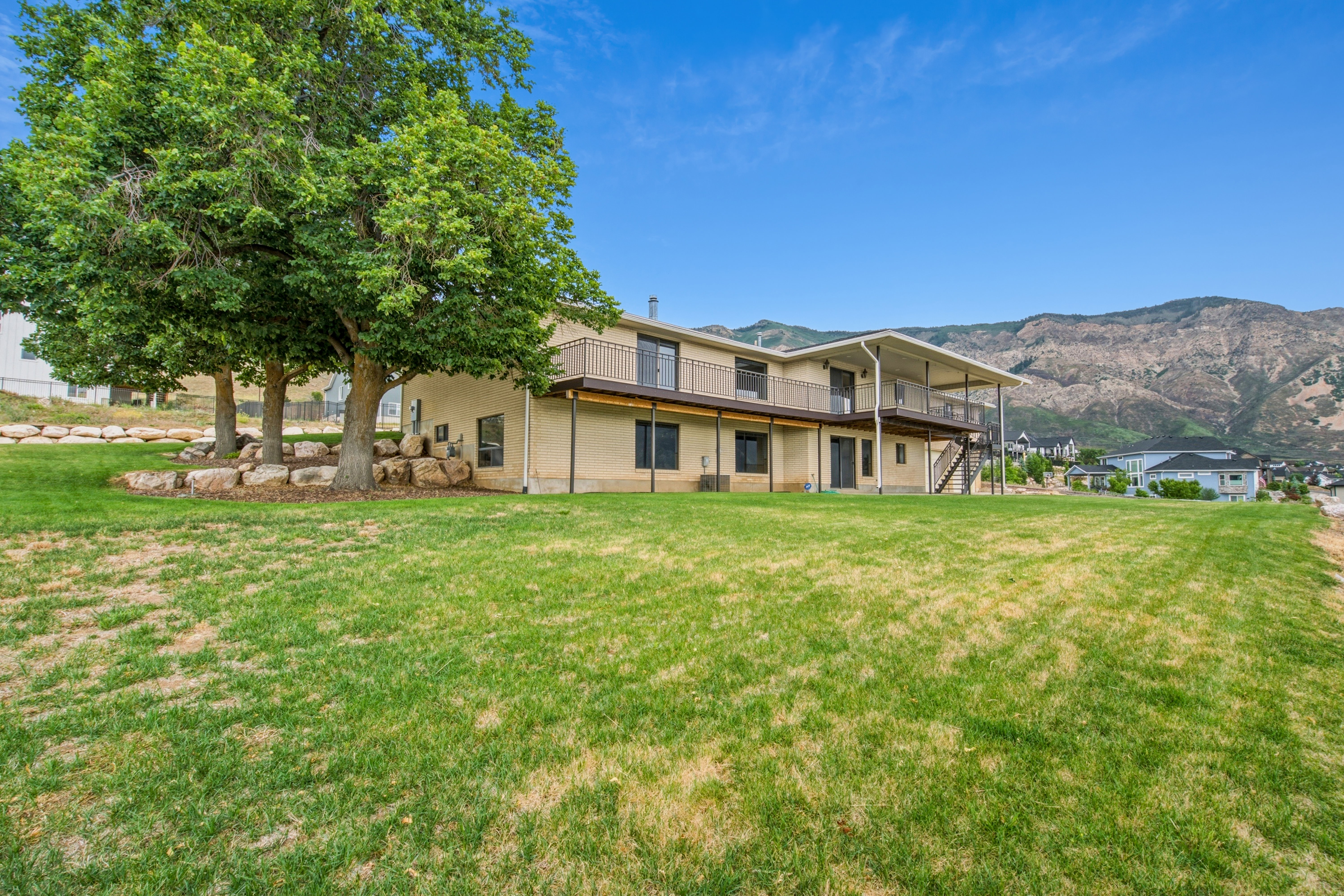 Expansive green lawn with mature trees and rock landscaping