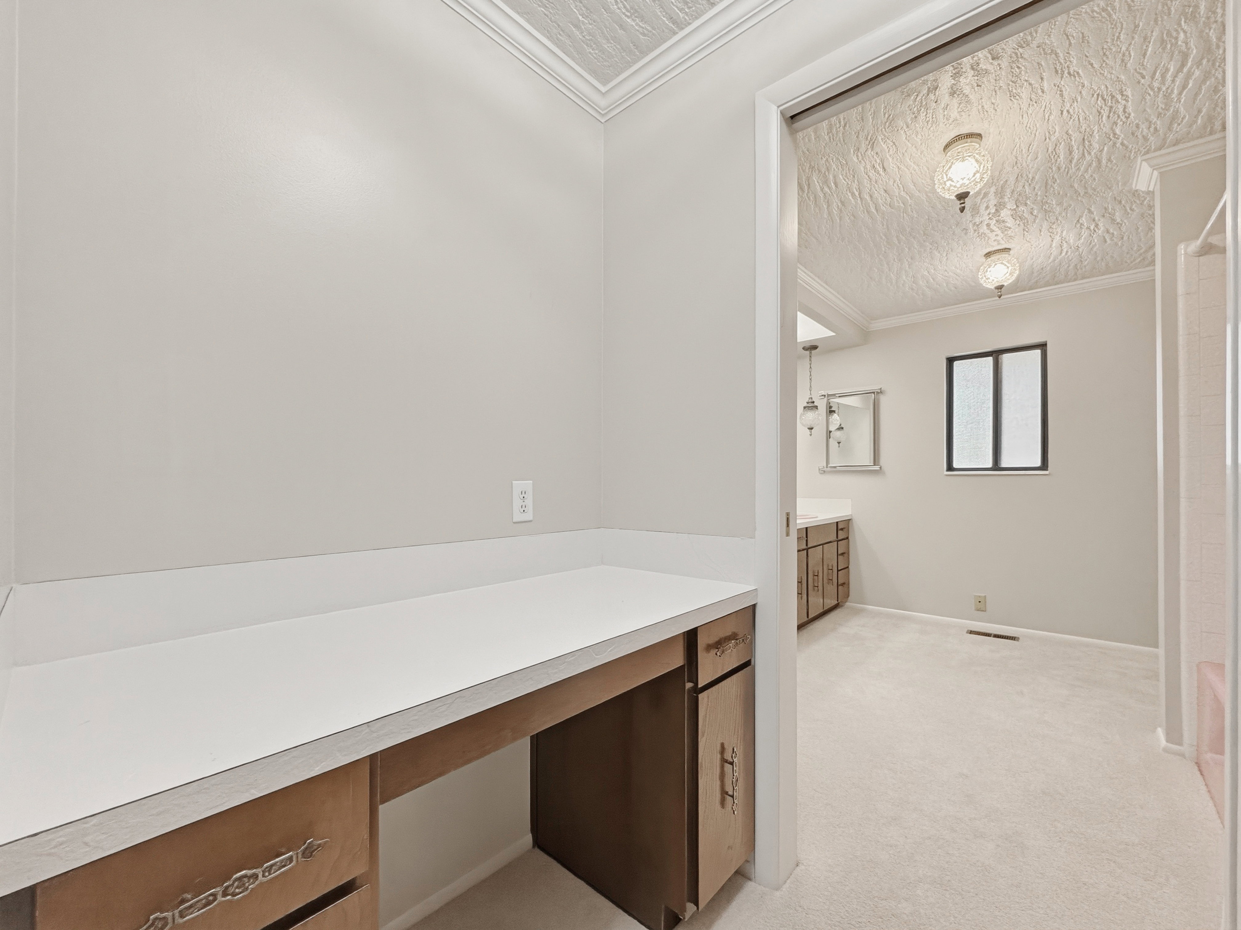 Built-in vanity with a white countertop and wood-finish cabinetry