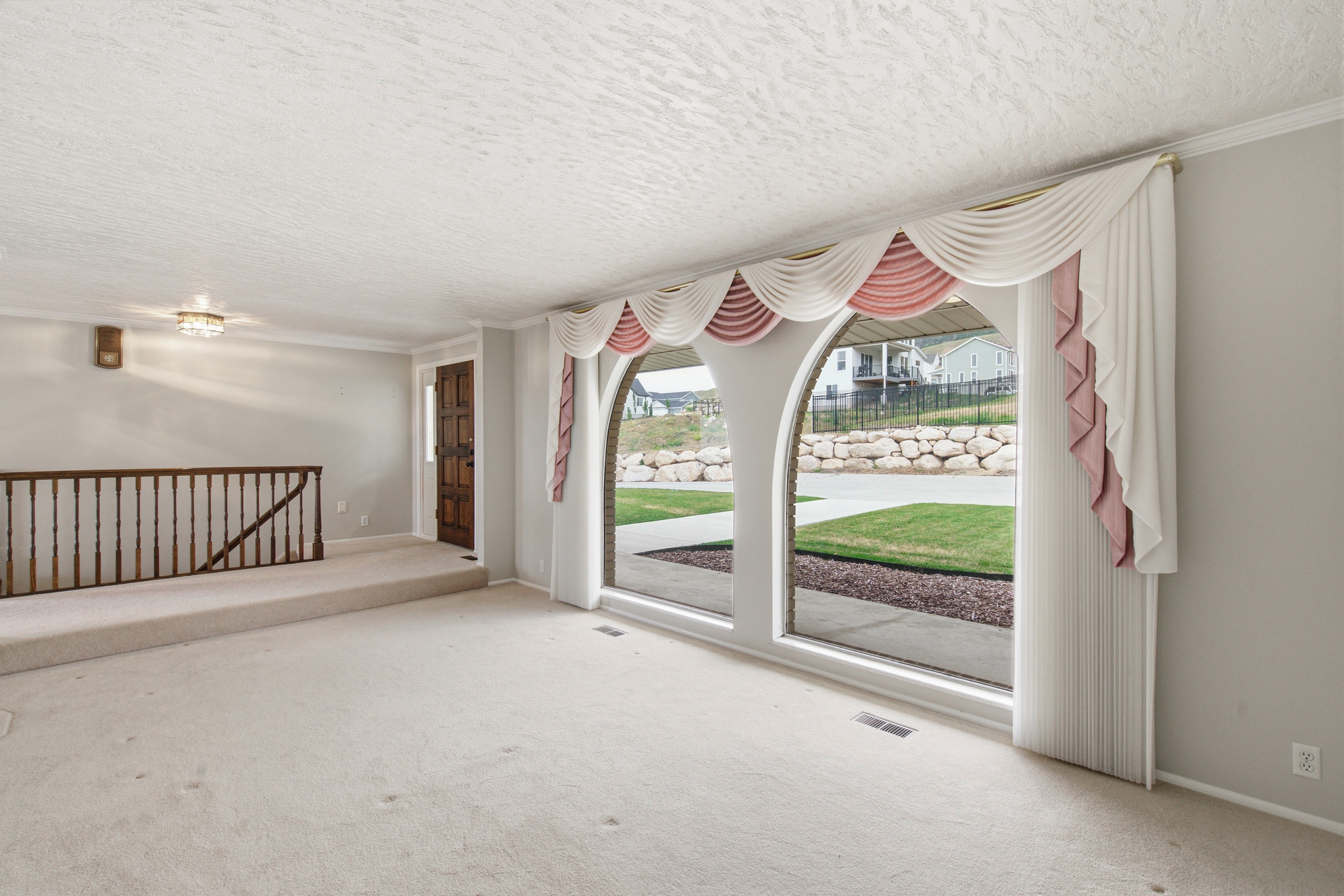 Arched windows with decorative valances overlooking a manicured lawn