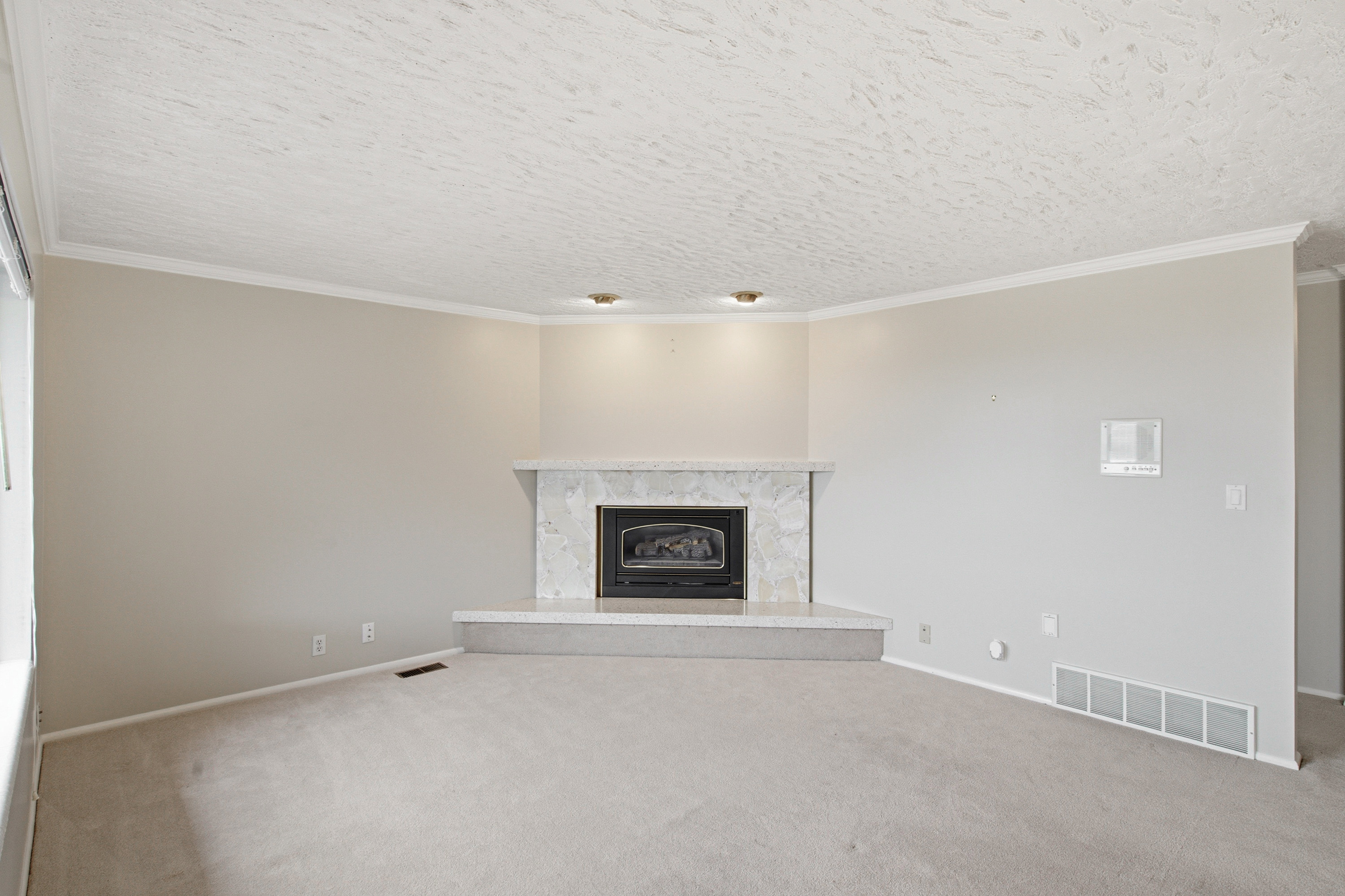 Corner fireplace featuring a light-toned stone surround and hearth