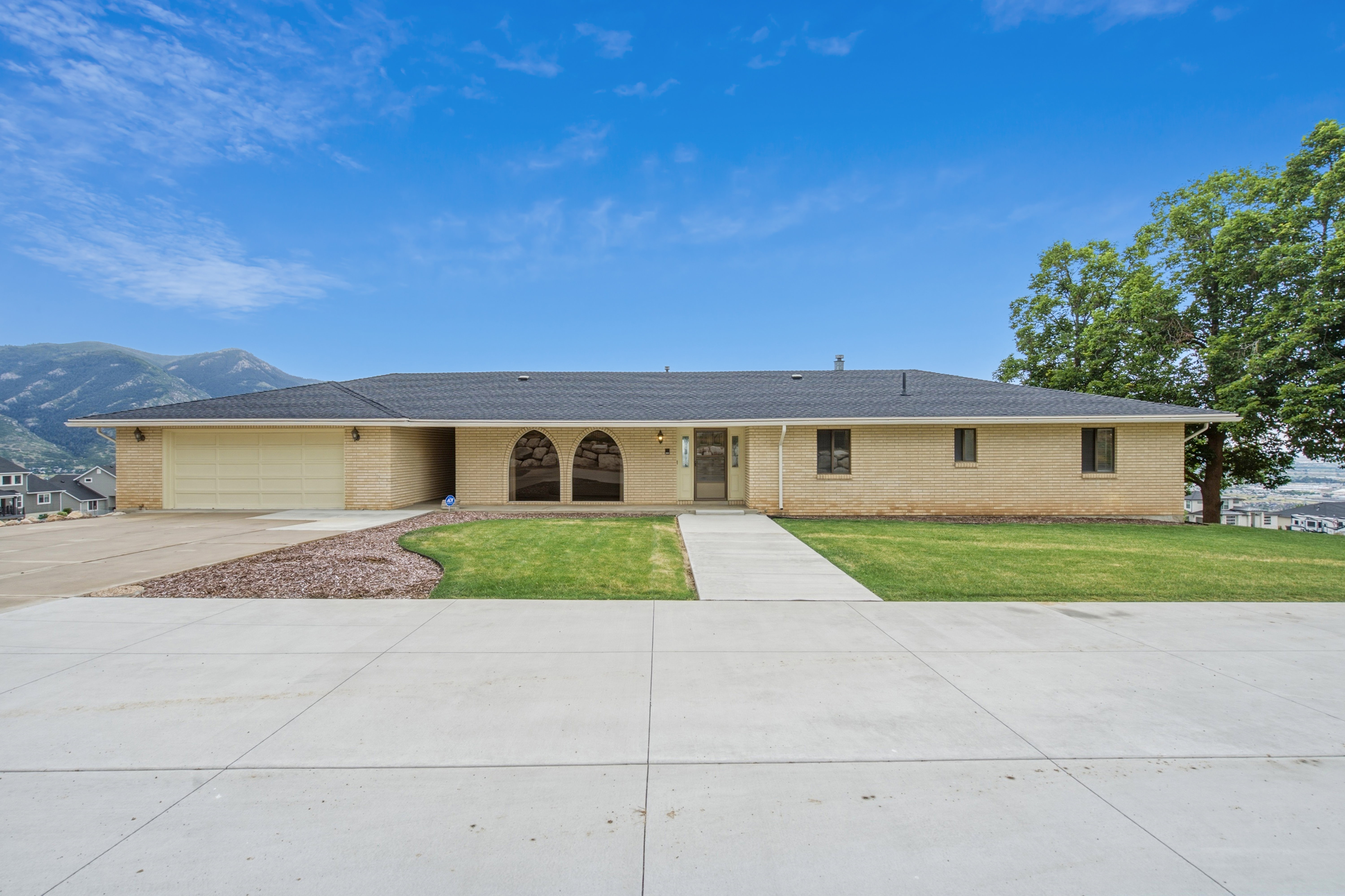 Single-story brick exterior with a dark roof and mountain backdrop