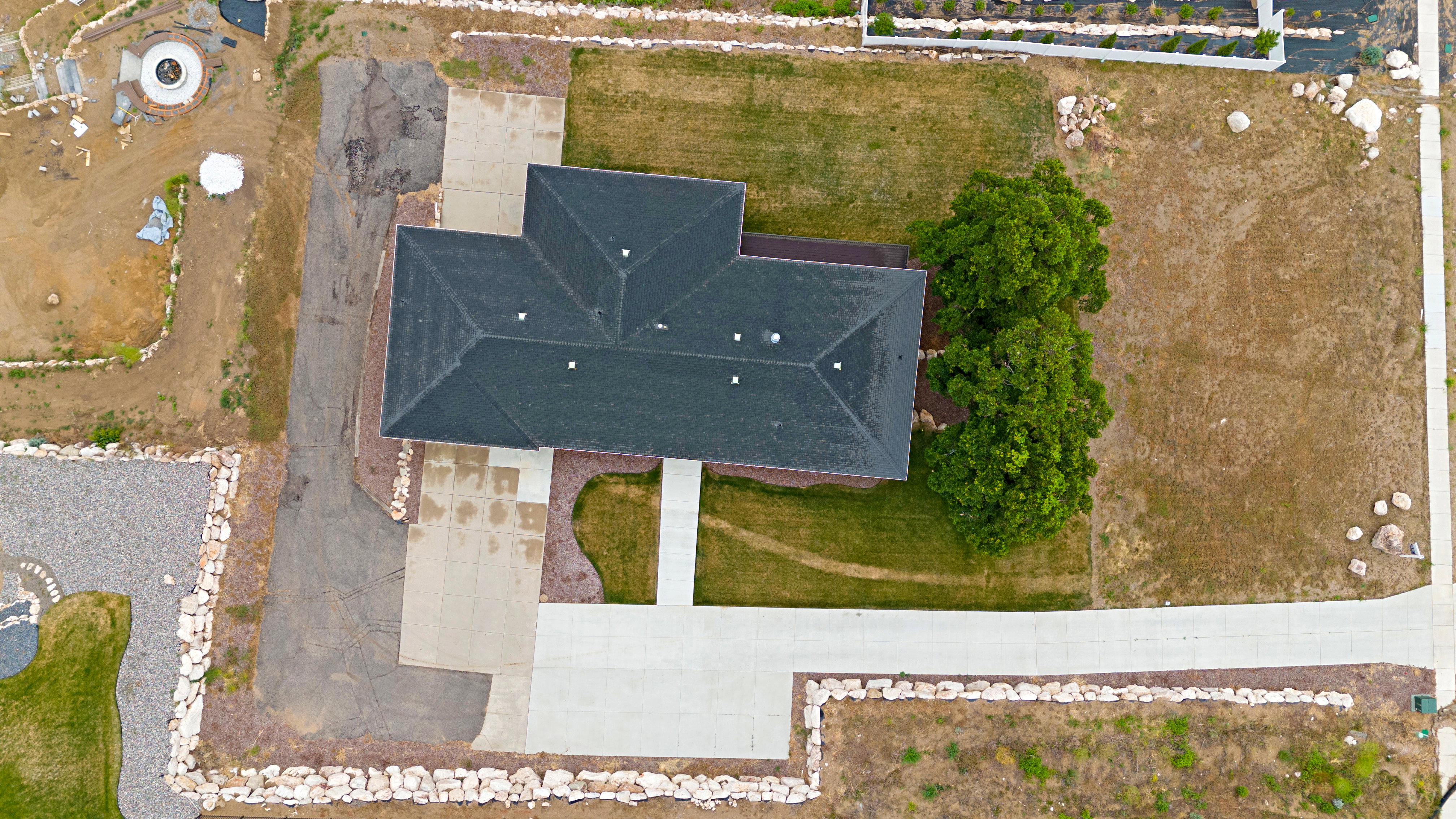 Property featuring a dark shingle roof, concrete driveways, and an expansive lawn