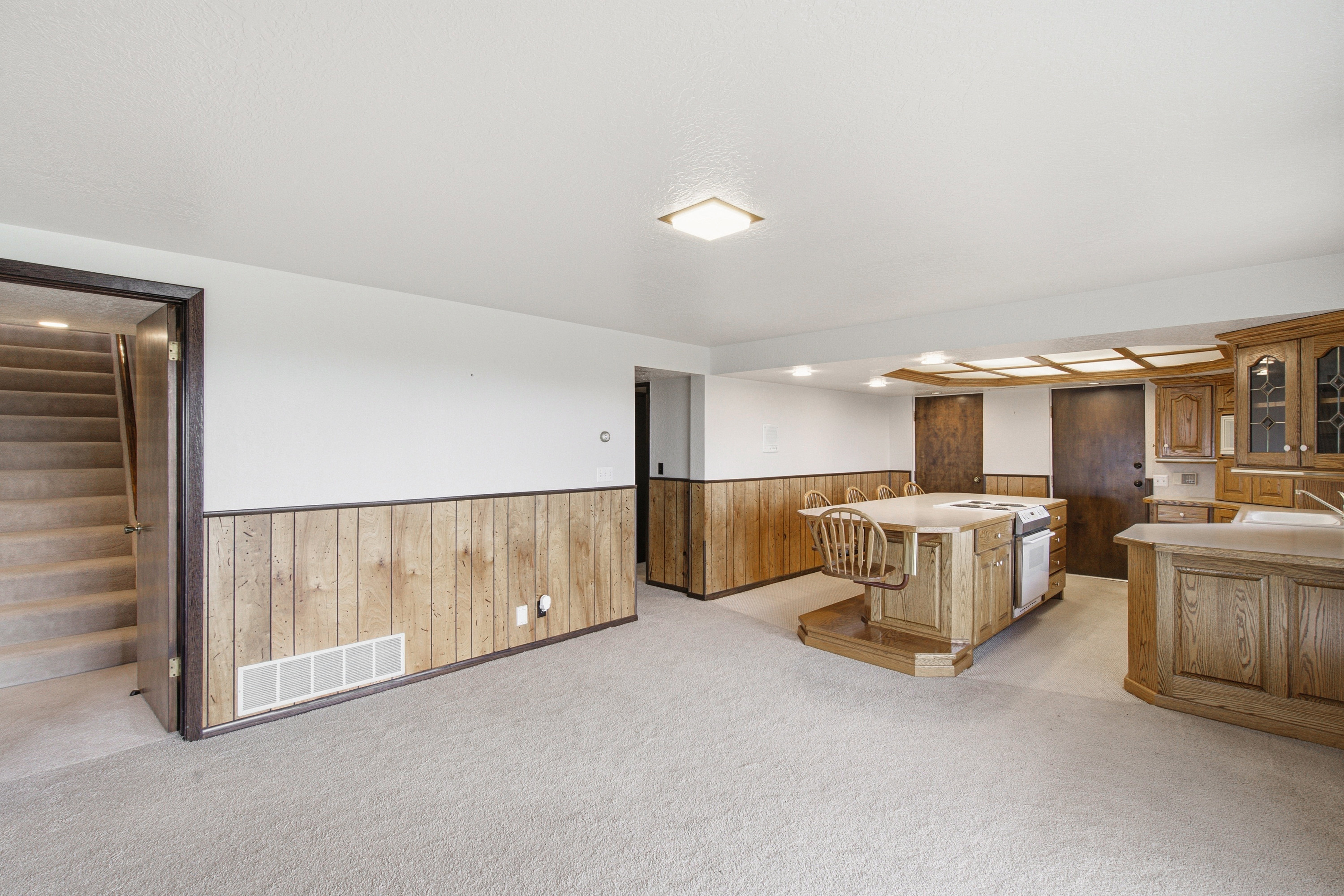 Open concept space with full kitchen featuring wood cabinetry and an island with built-in seating