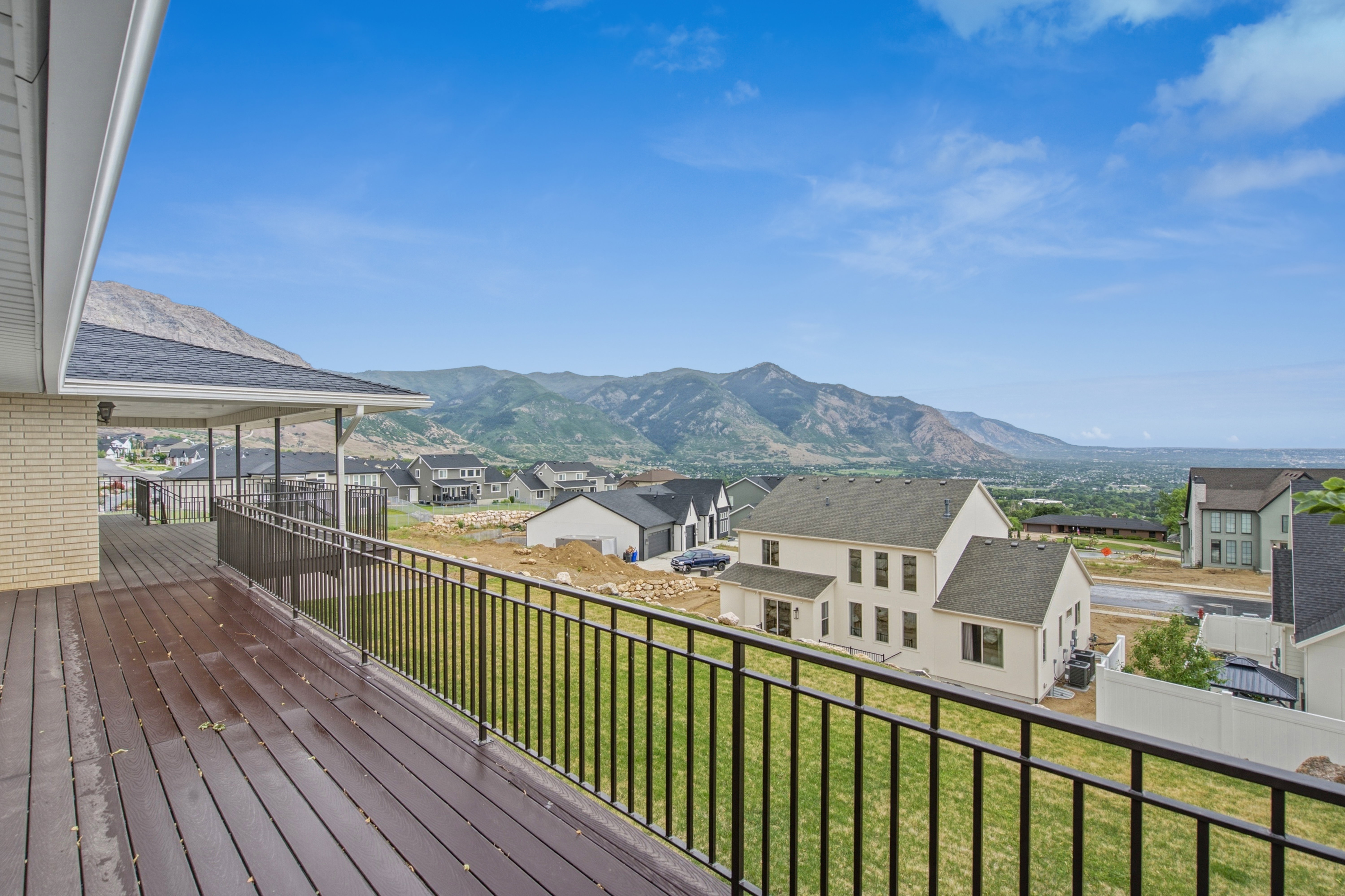Expansive covered deck featuring wood-finish flooring and black metal railings