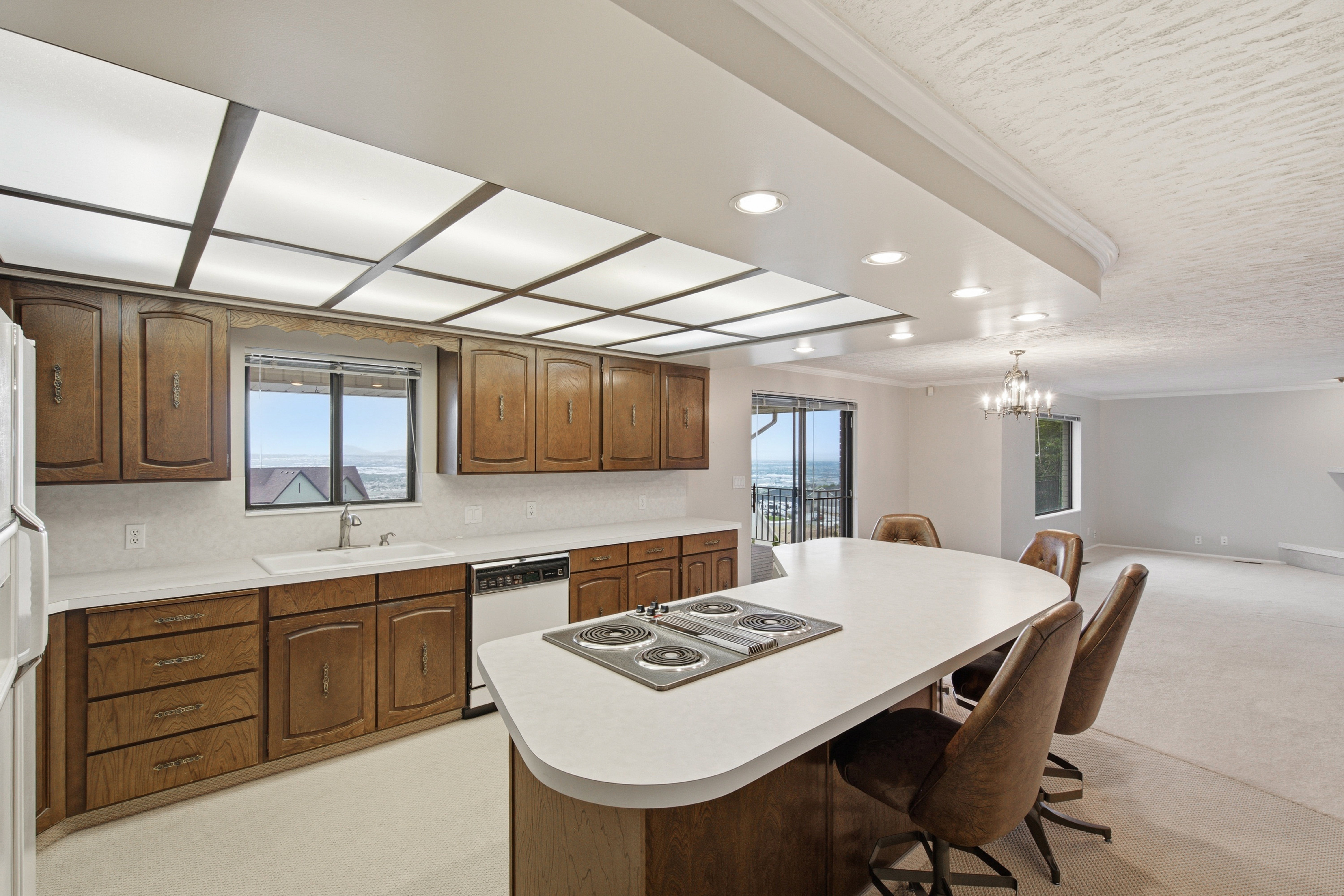 Kitchen featuring wood cabinetry, white countertops, built-in electric cooktop island, and recessed lighting