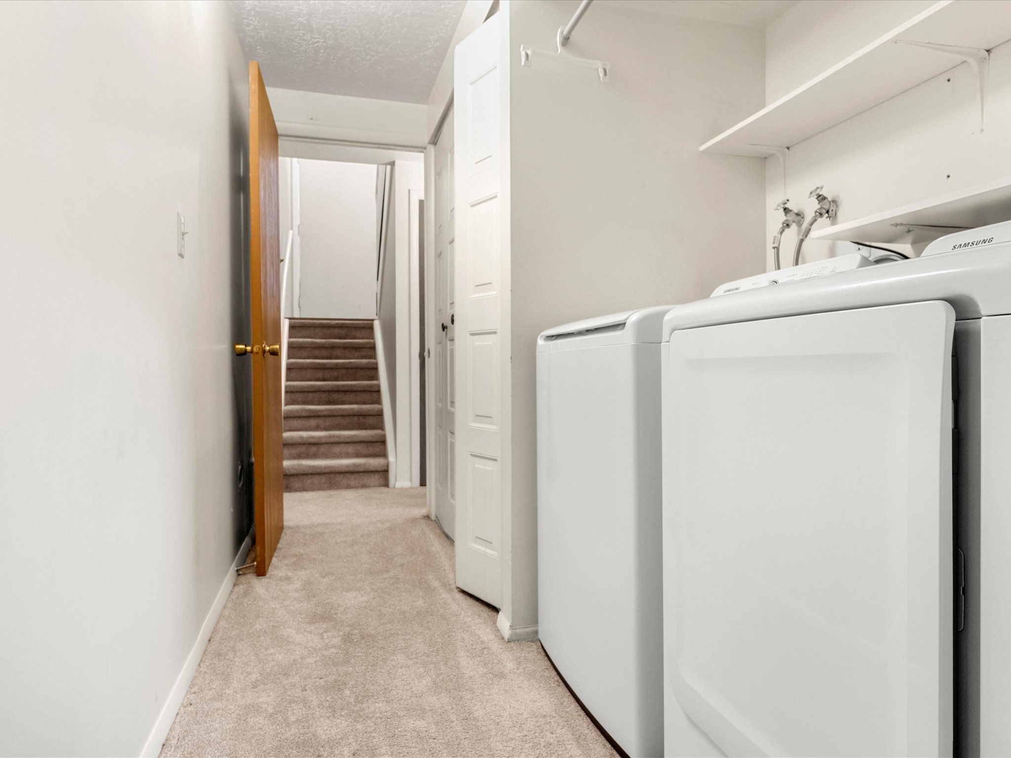 Dedicated laundry area featuring a washer and dryer, integrated shelving, and a hanging rod
