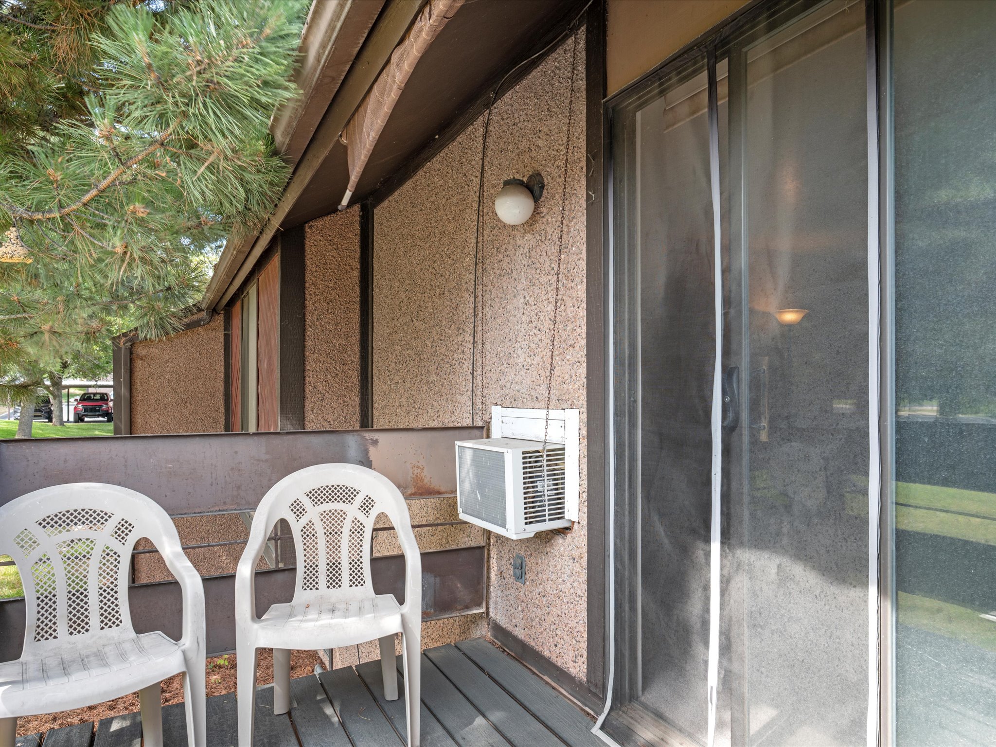 Private Deck featuring a sliding glass door, a wall-mounted light fixture, and a compact air conditioning unit