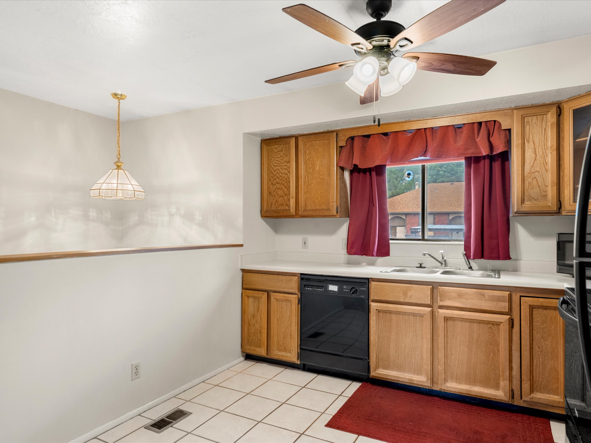 Kitchen area featuring wood cabinetry, white countertops, tile flooring, and a ceiling fan with integrated lighting