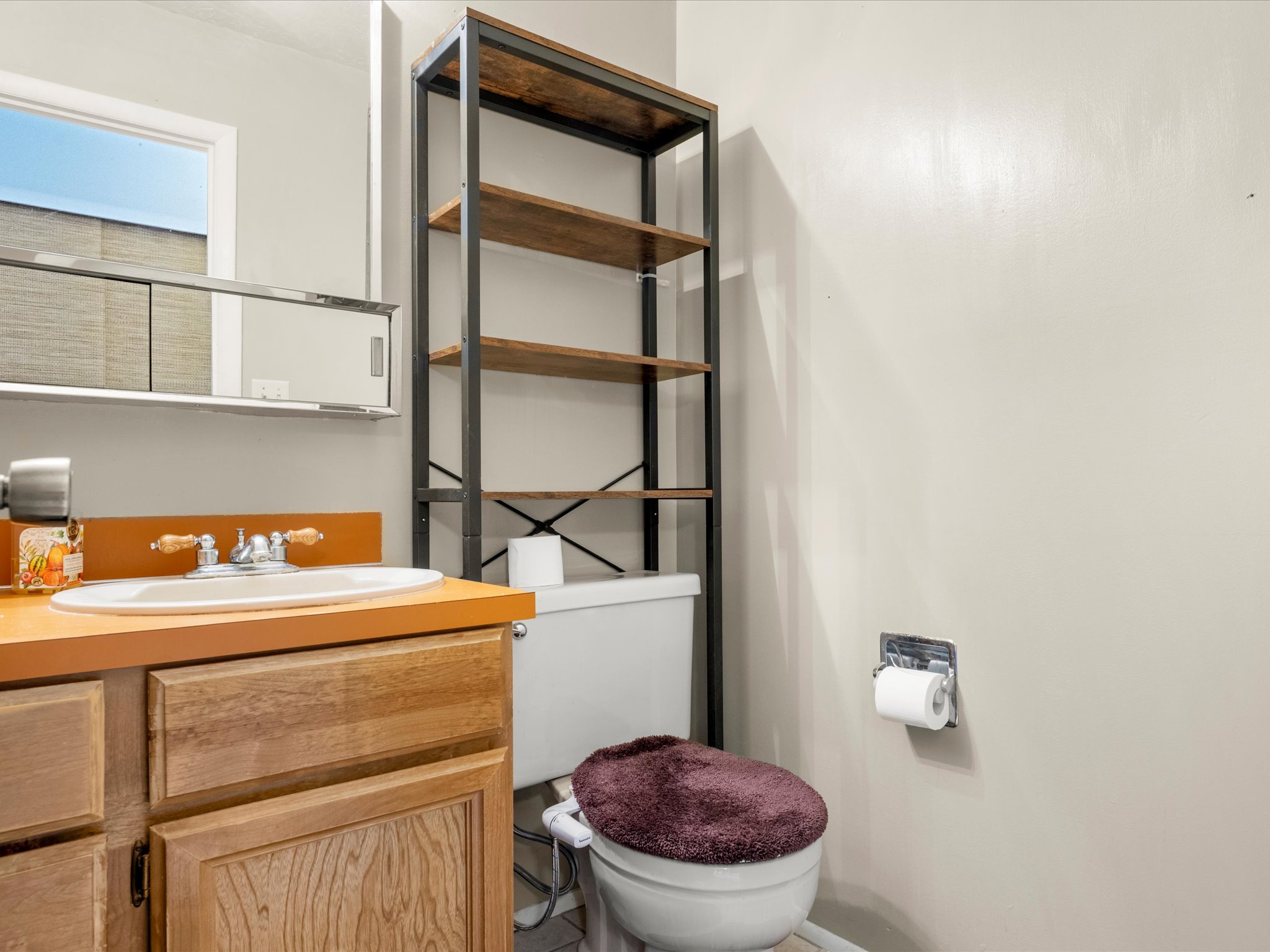 Bathroom vanity with wood-finish cabinetry, a white oval sink.