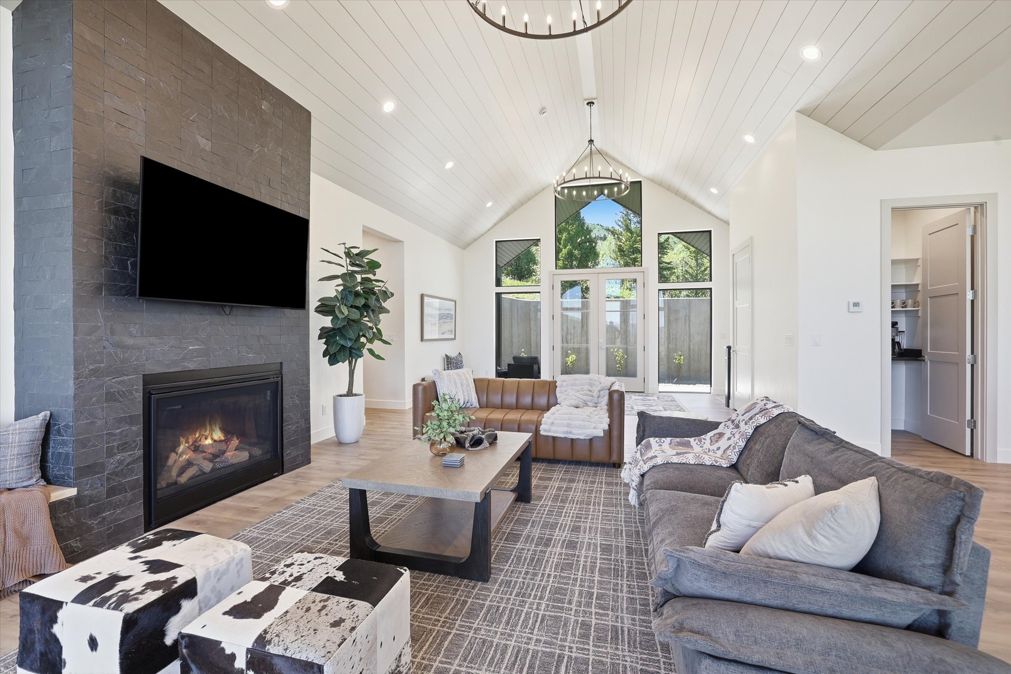 Open-concept living area featuring a vaulted ceiling with wood-finish paneling, a chandelier, and recessed lighting