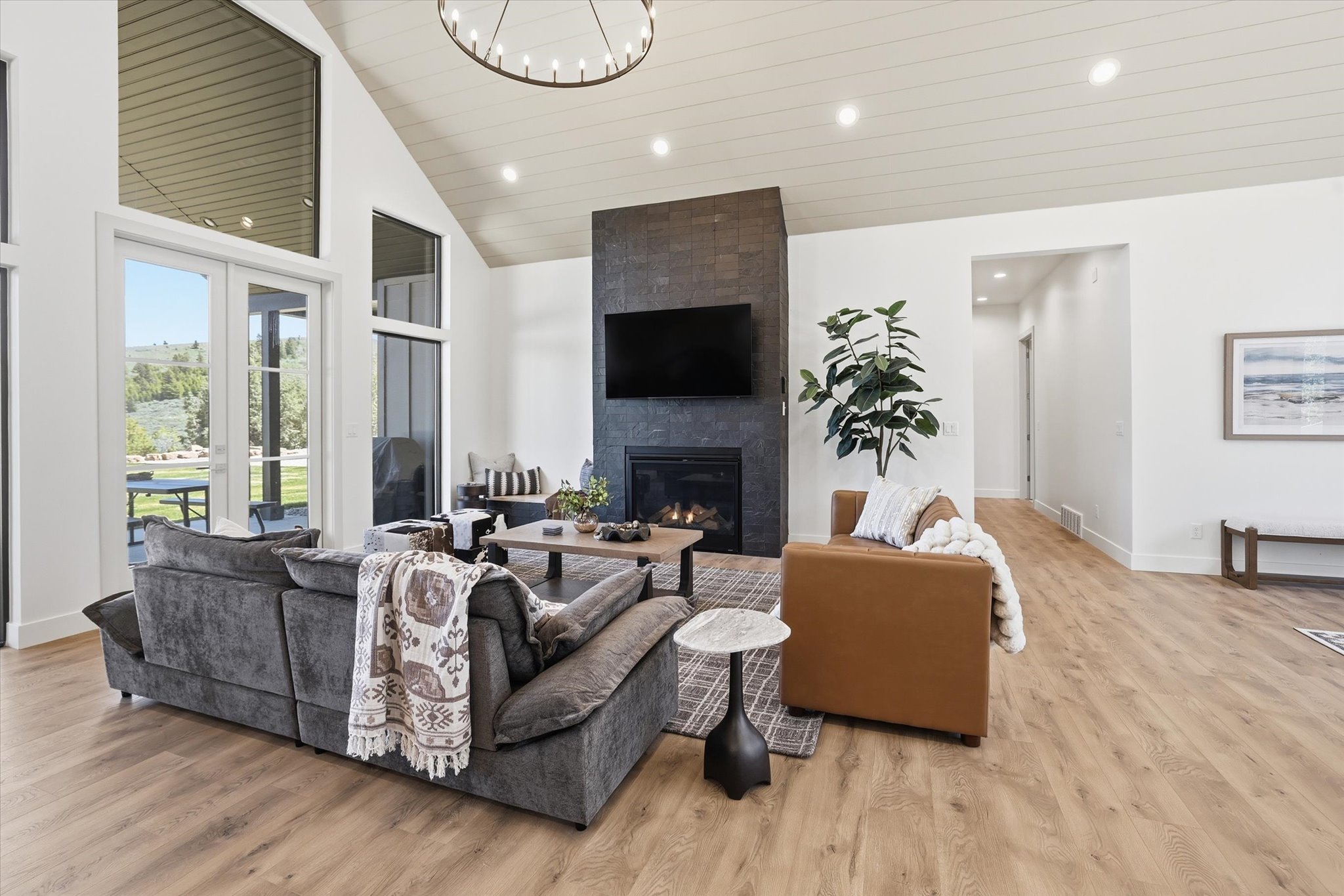 Spacious living area featuring a vaulted ceiling with wood-finish paneling, a contemporary chandelier, and recessed lighting