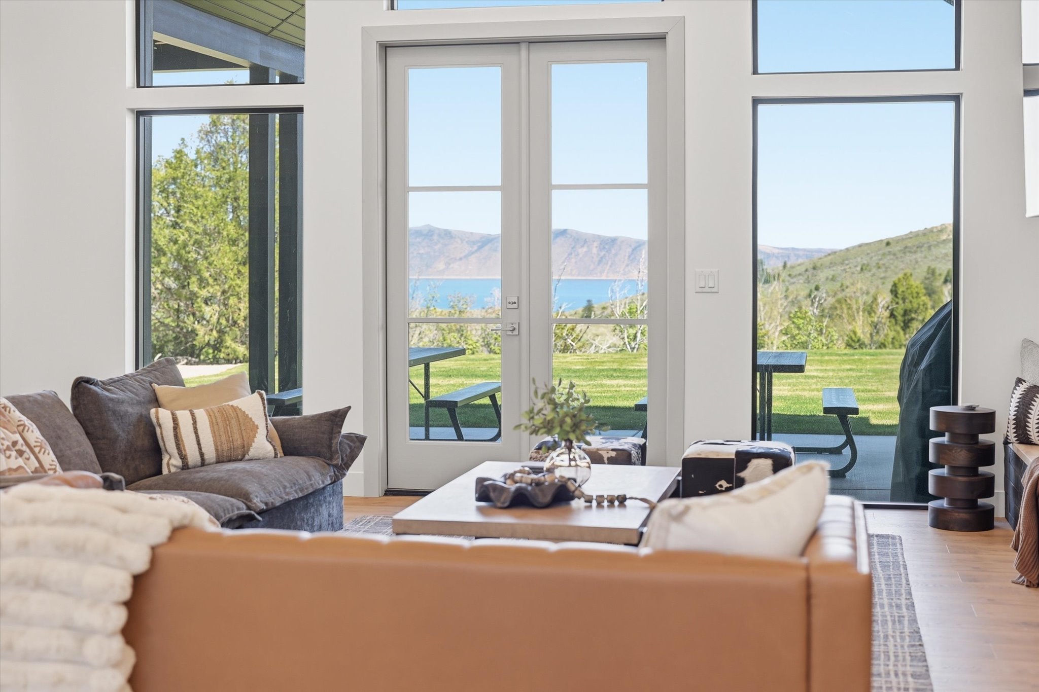 French doors opening to an expansive outdoor space with a distant water body and surrounding hills