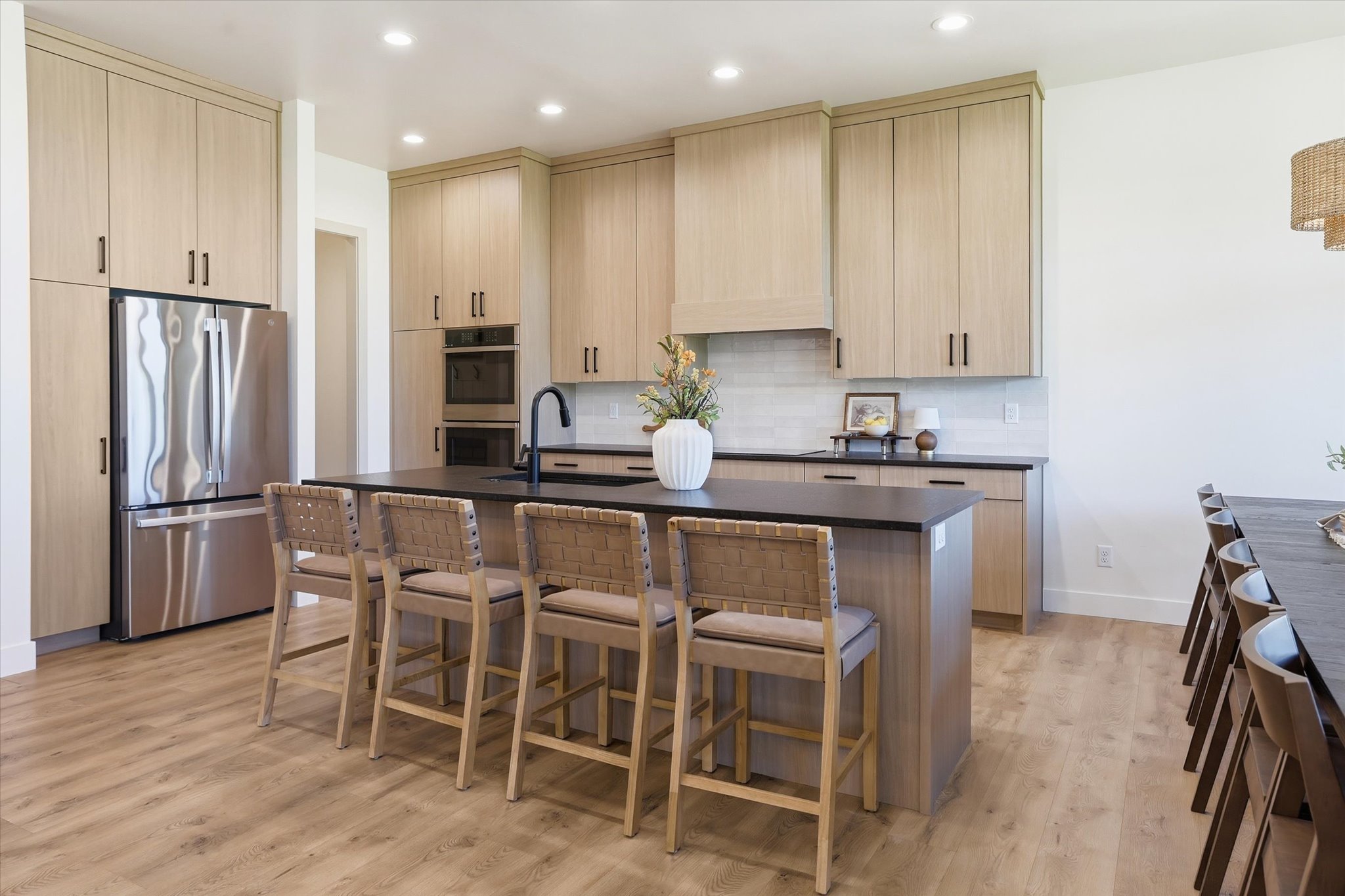 Spacious kitchen featuring light wood-finish cabinetry, black countertops, and wood-finish flooring