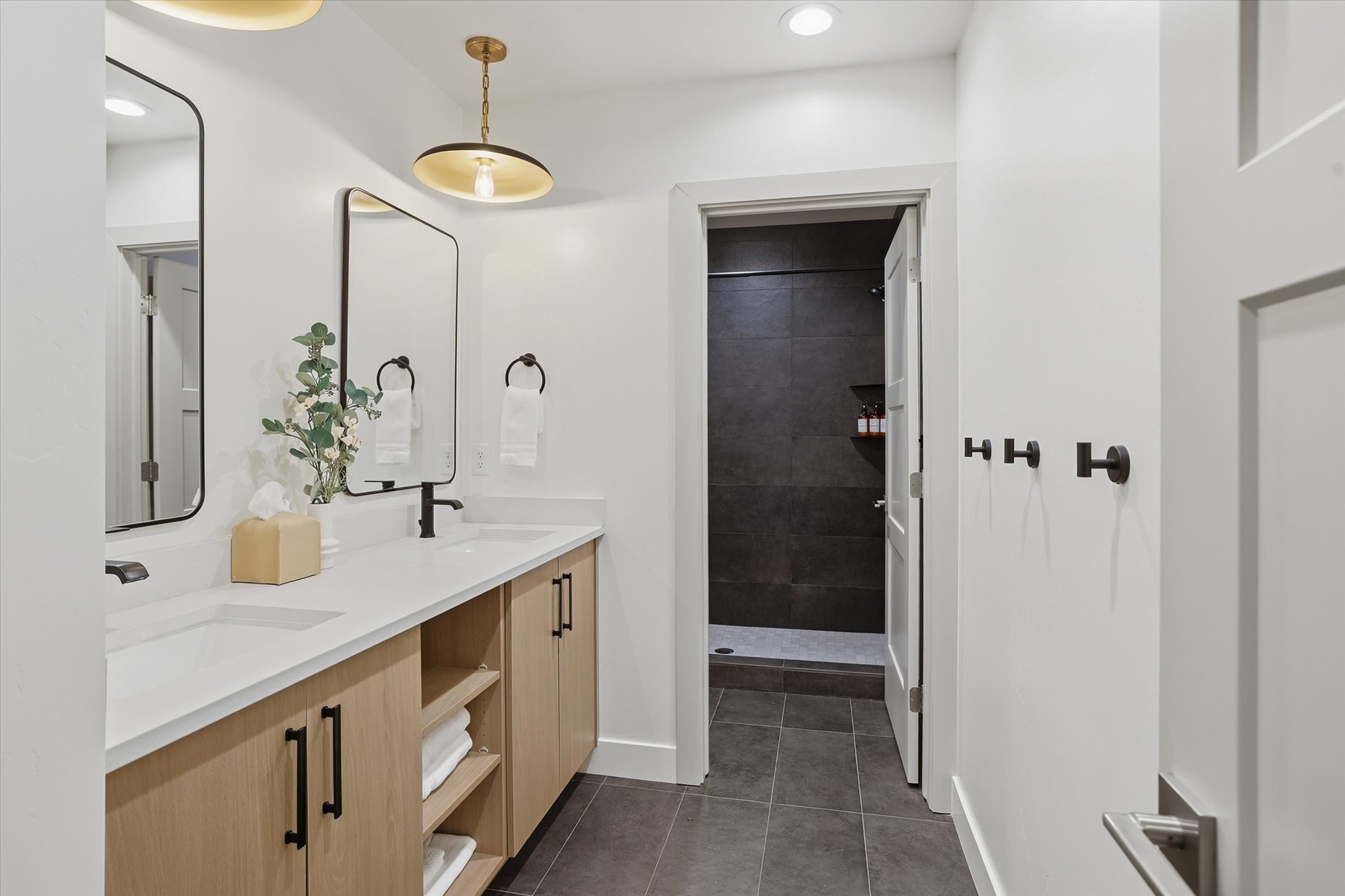 Dual vanity featuring light wood-finish cabinetry, integrated sinks, and matte black fixtures