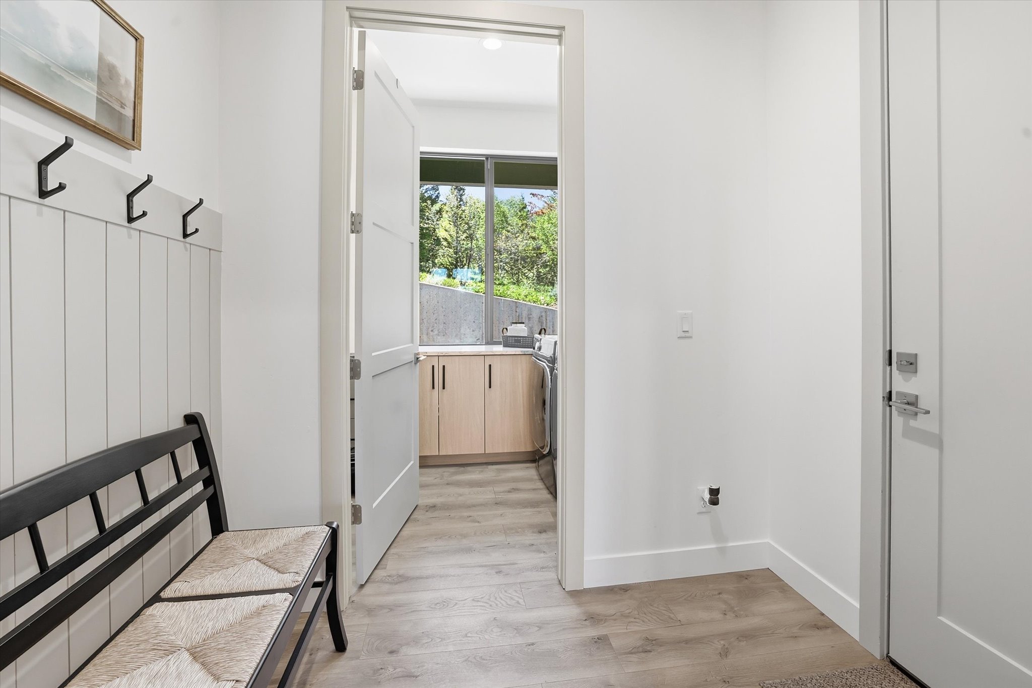 Entryway featuring a wainscoting accent wall with black coat hooks, wood-finish flooring, and a solid core door