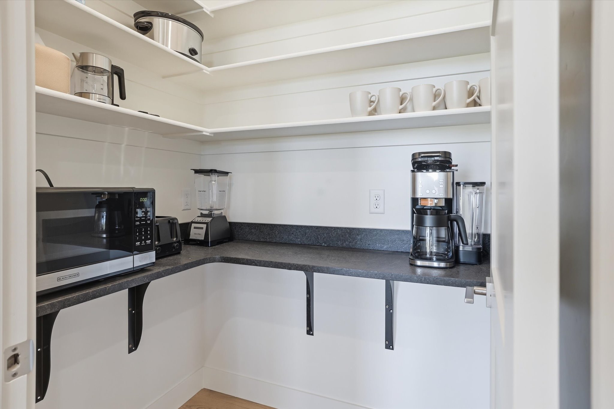 Dedicated pantry space featuring a built-in countertop, open shelving, and electrical outlets