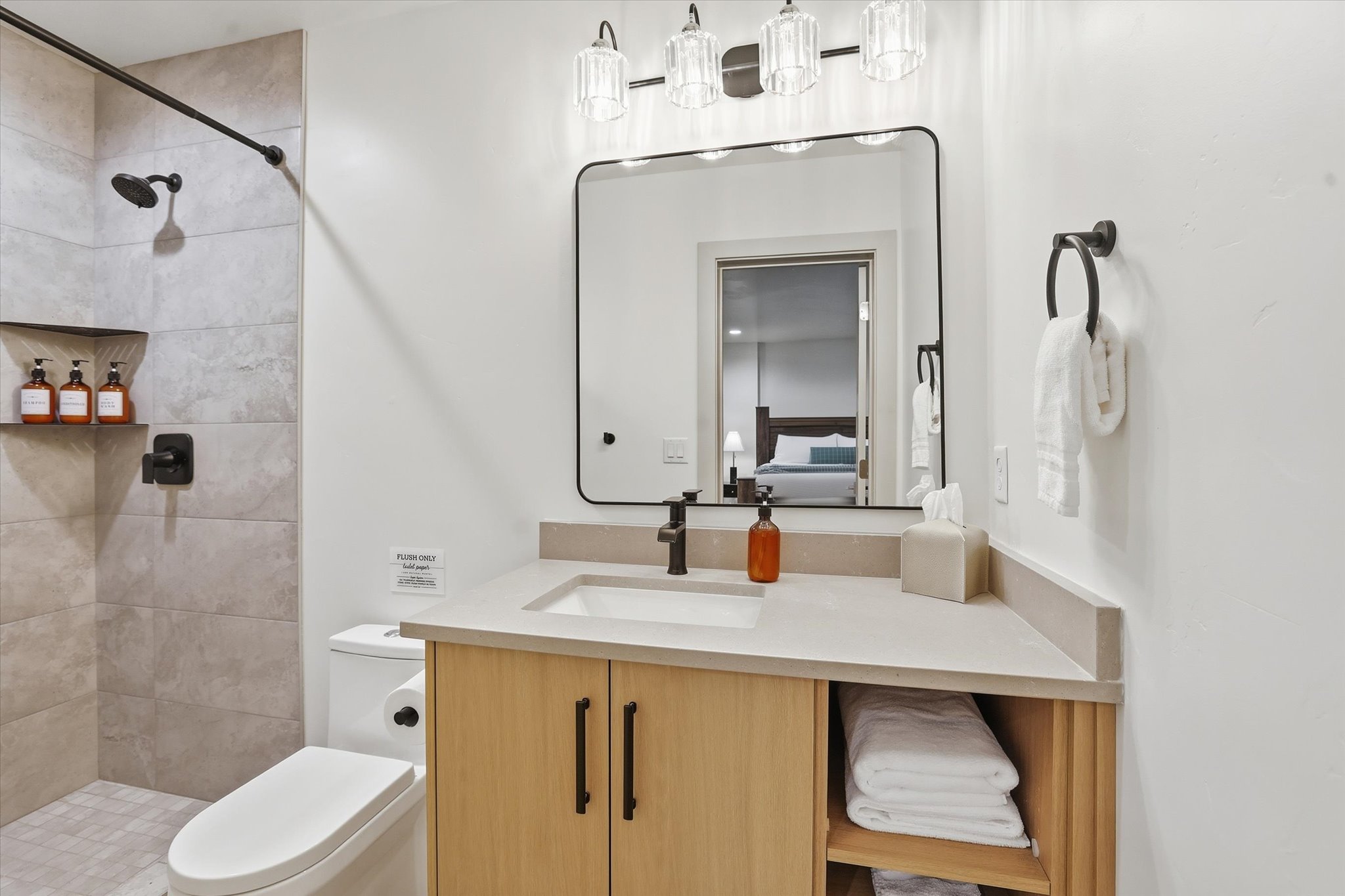 Bathroom featuring a light wood-finish vanity with an integrated sink, a large rectangular mirror, and a three-light fixture