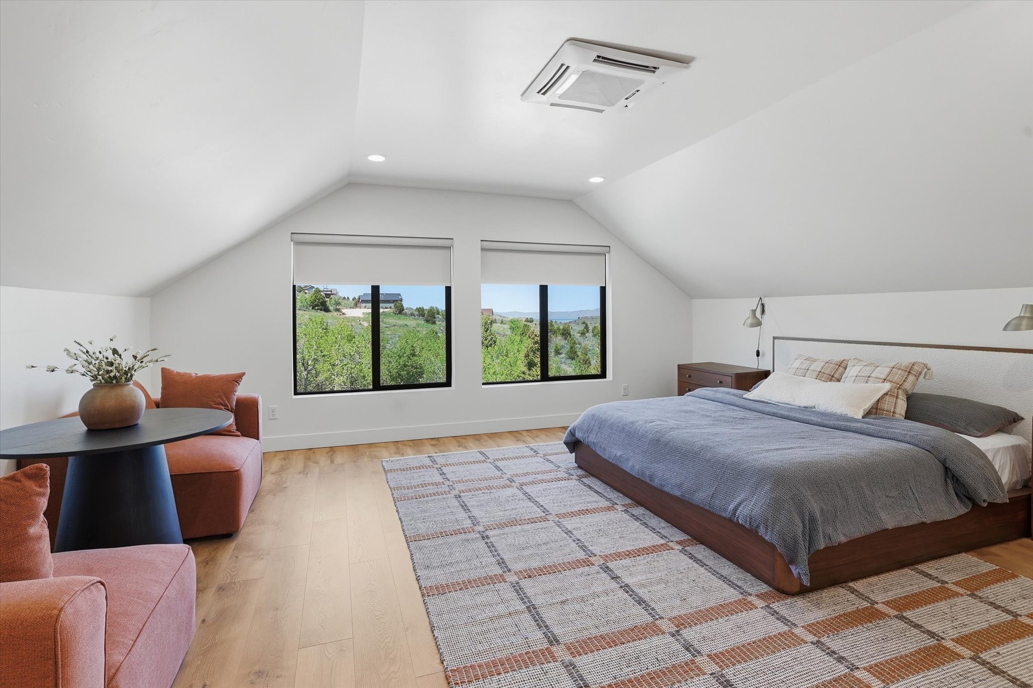 Spacious room featuring vaulted ceilings, a large area rug, and wood-finish flooring