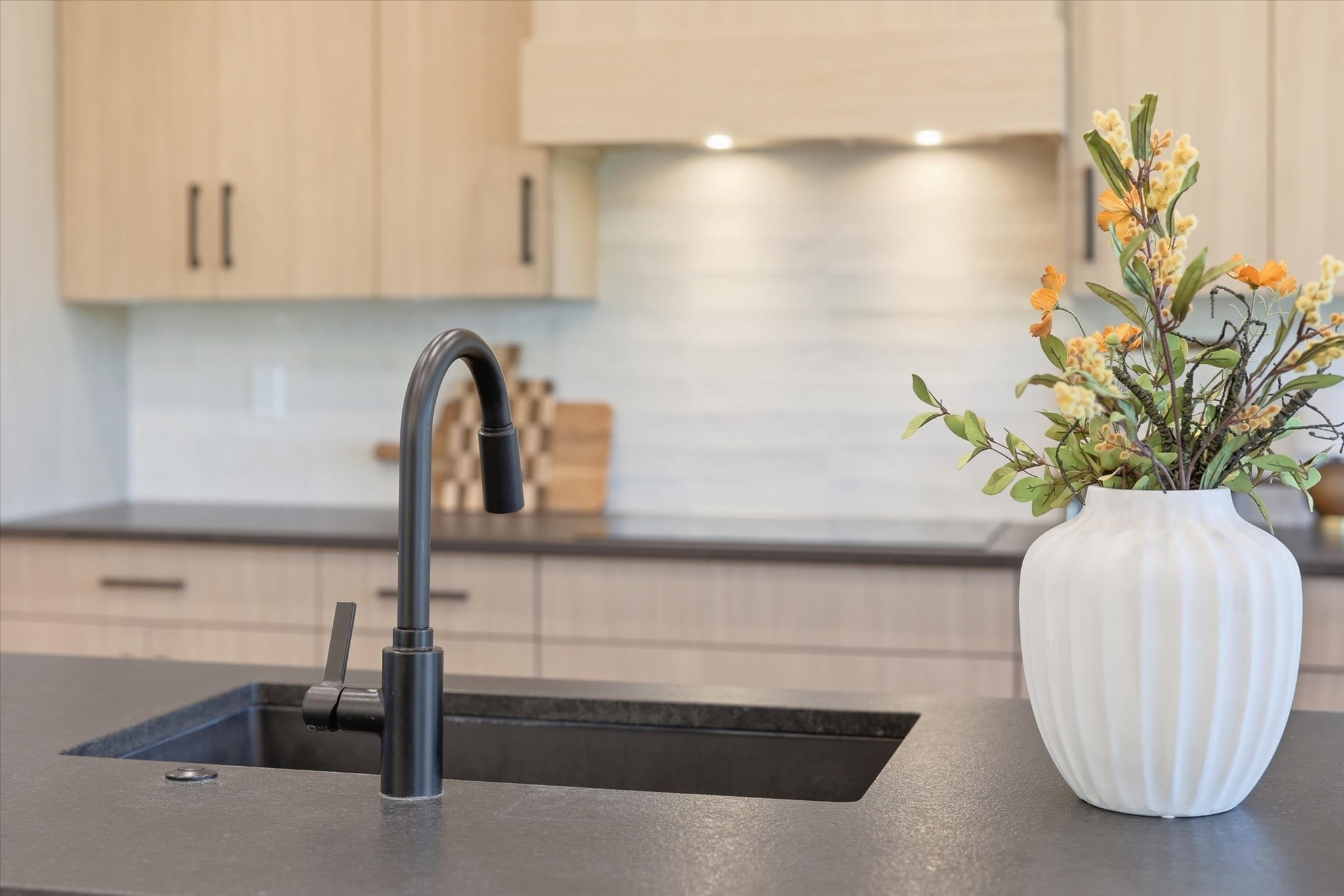 Kitchen island featuring a dark composite sink and a matte black gooseneck faucet