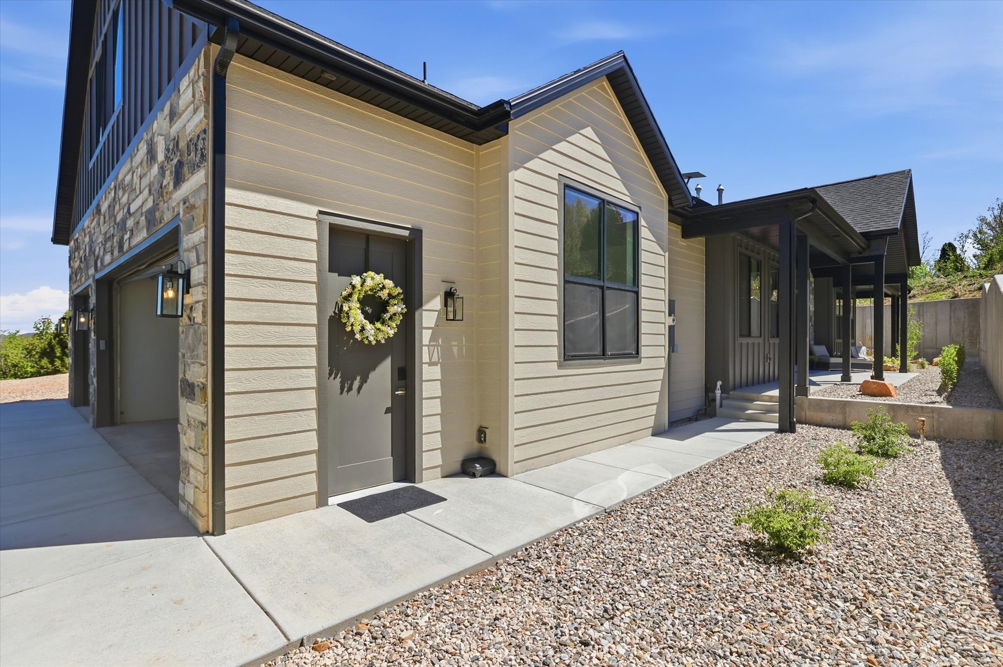 Modern facade featuring a stone veneer accent, horizontal siding, and a covered entry