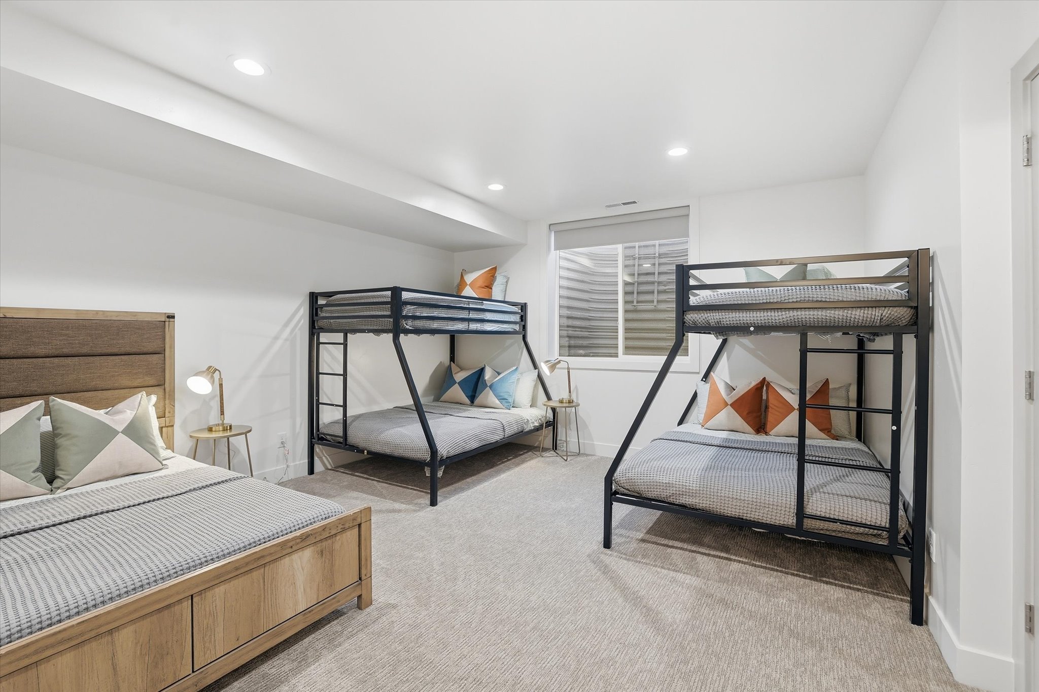 Carpeted bedroom with recessed lighting, a window with horizontal blinds, and a white door with a silver handle