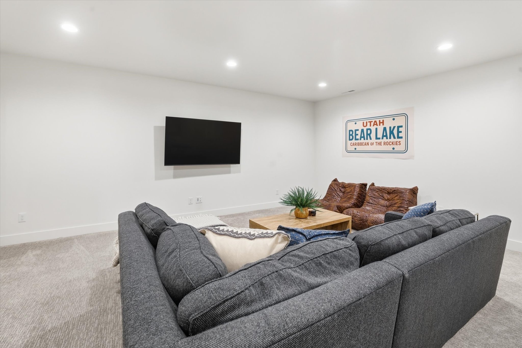Spacious interior room featuring light gray carpeting, recessed lighting, and white baseboards