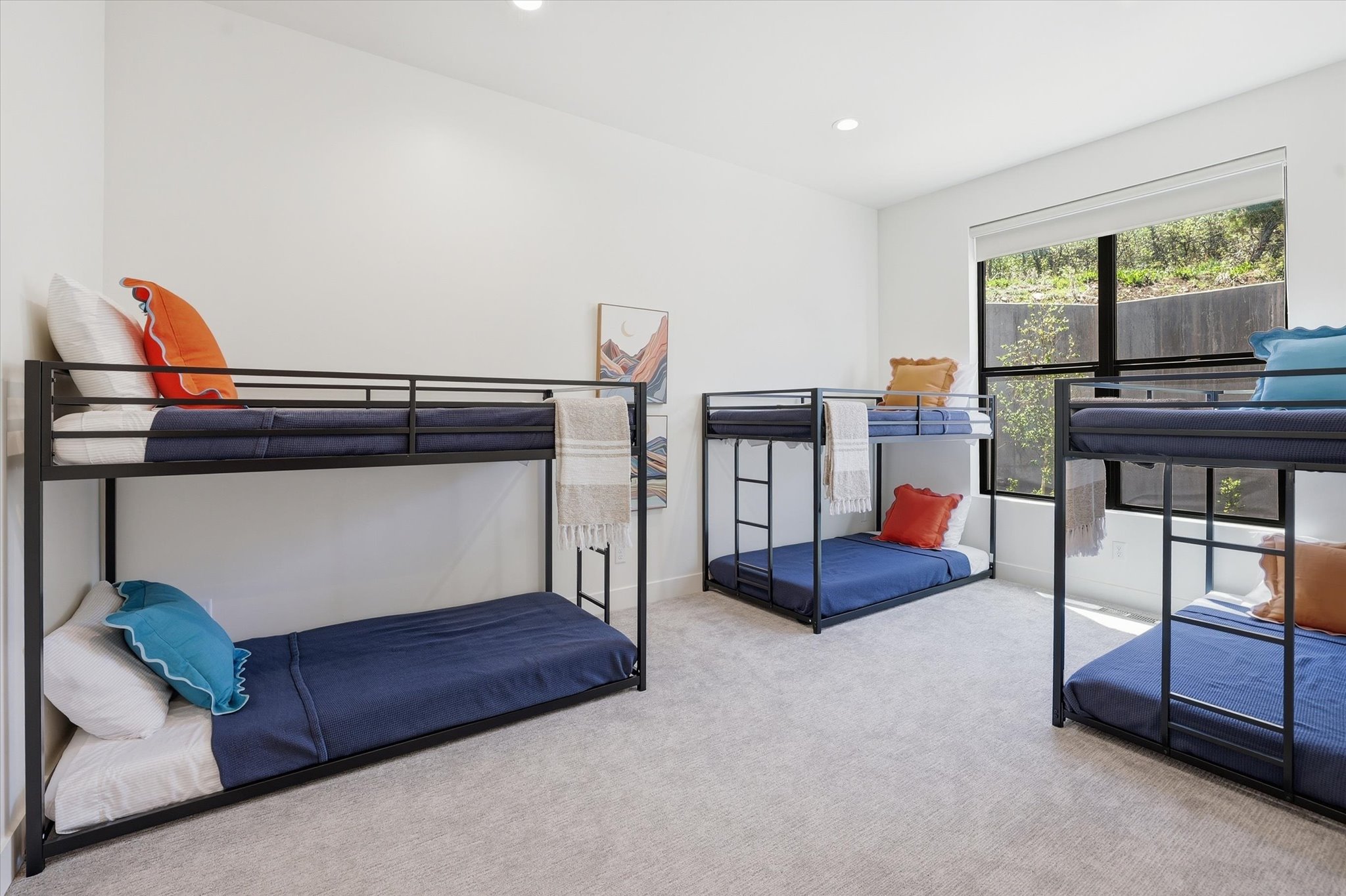 Spacious room featuring light gray carpeting, crisp white walls, recessed lighting, and a large window with black framing