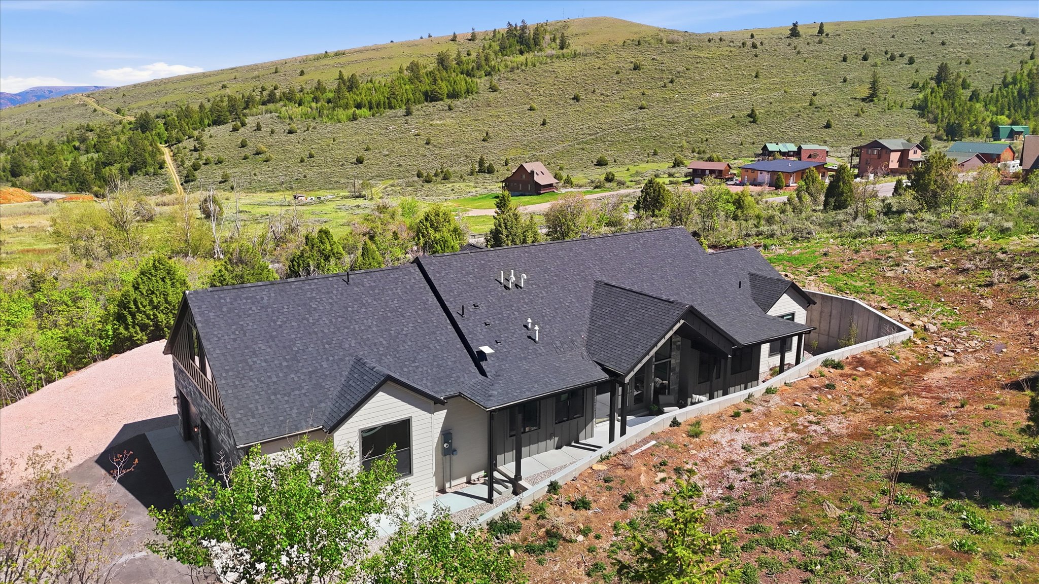 Contemporary-style residence featuring a dark gray shingle roof and light gray siding with dark trim accents