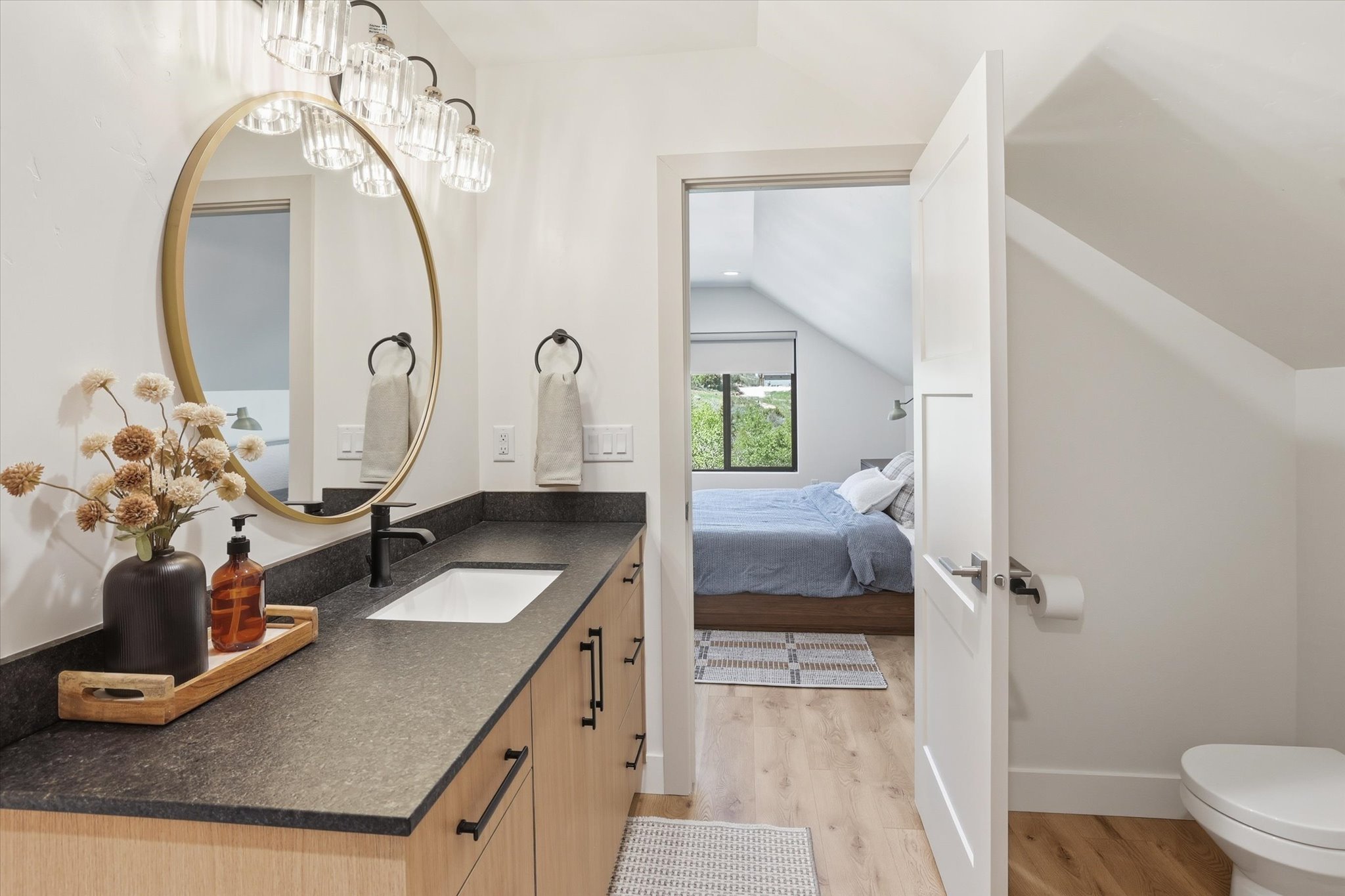 Bathroom vanity with an undermount sink, dark countertop, and light wood-finish cabinetry