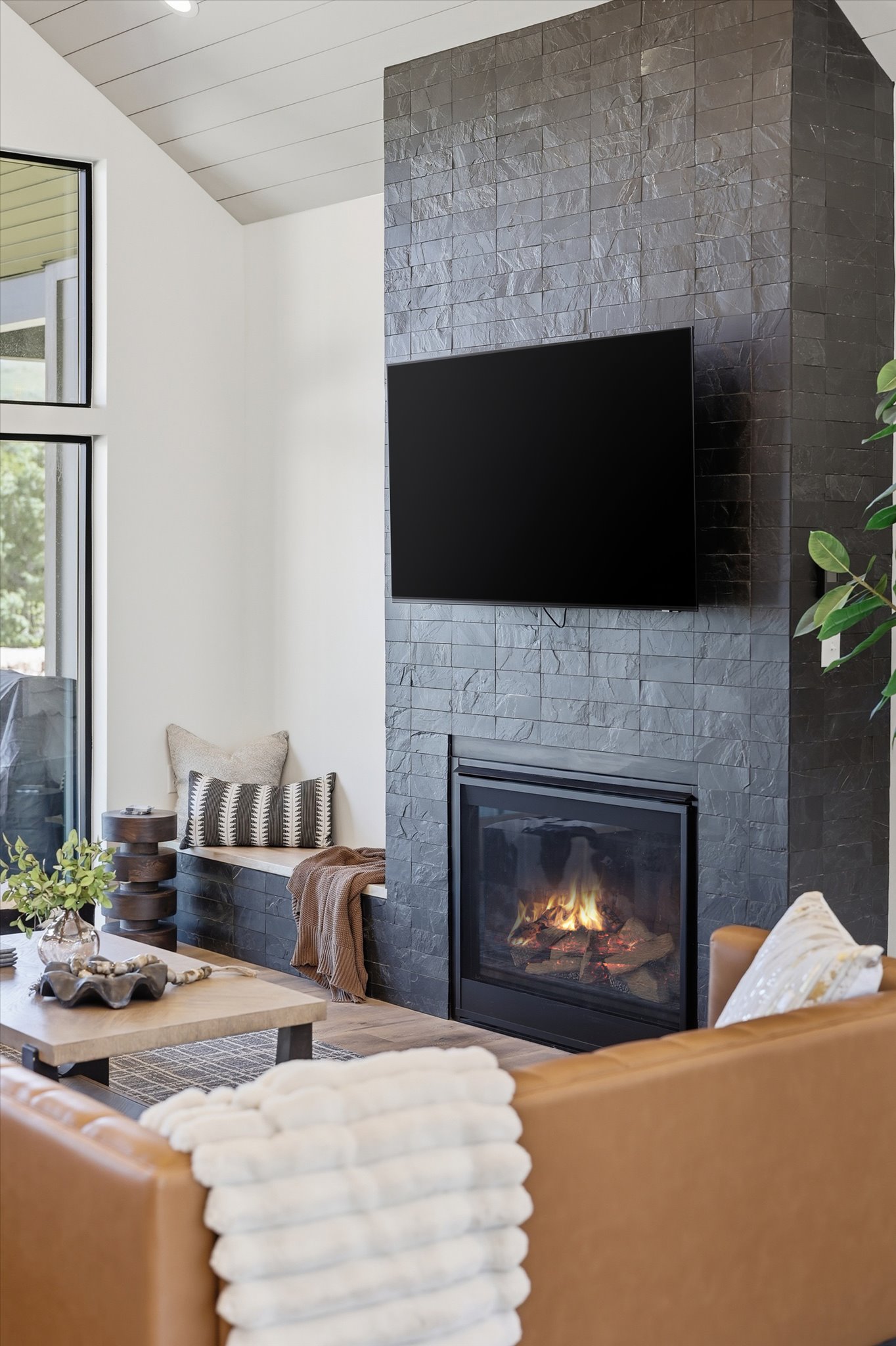 Stone-clad fireplace with built-in hearth seating and a mounted media display