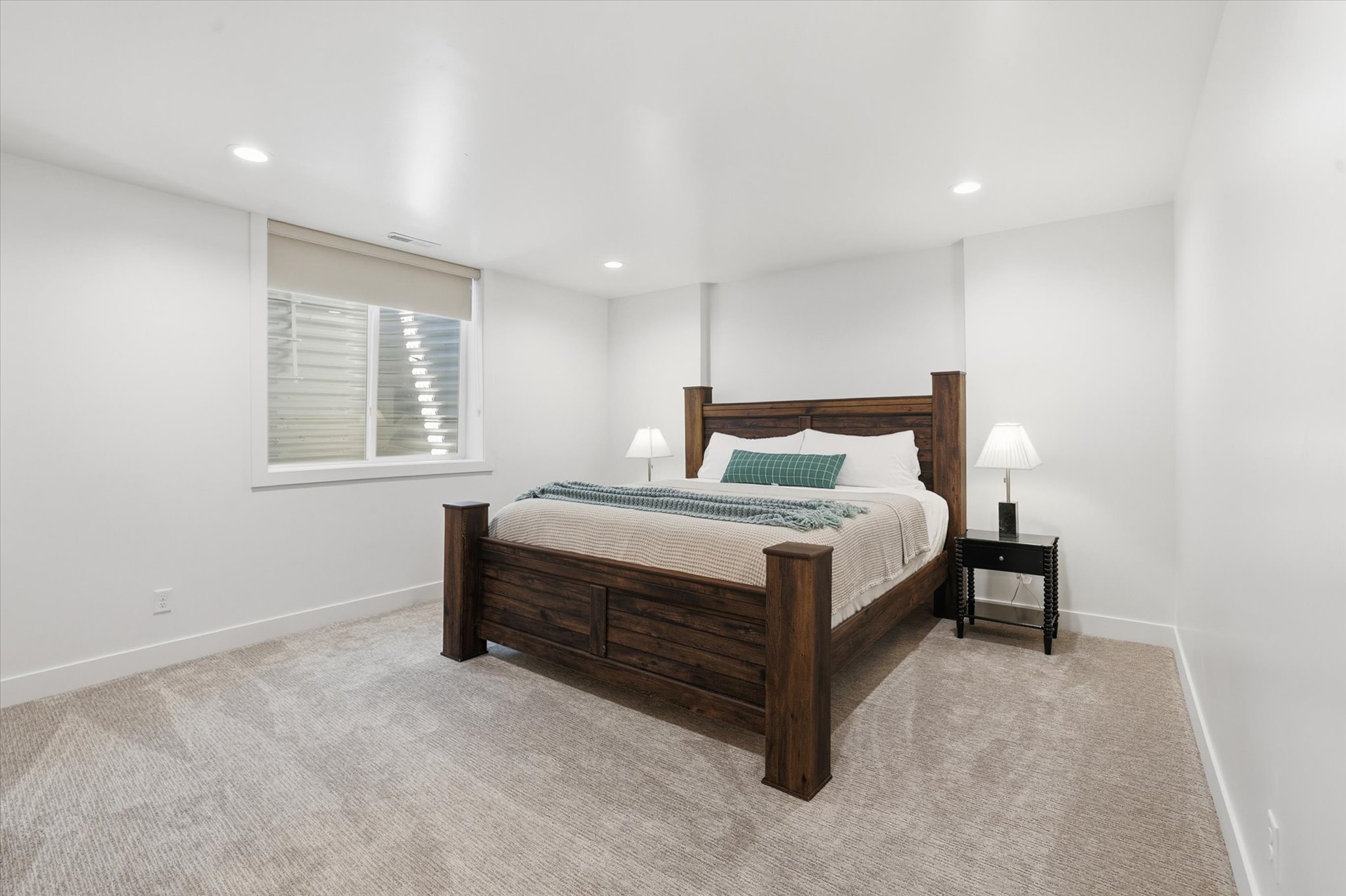 Spacious bedroom featuring light-toned carpet flooring, white walls, and recessed lighting
