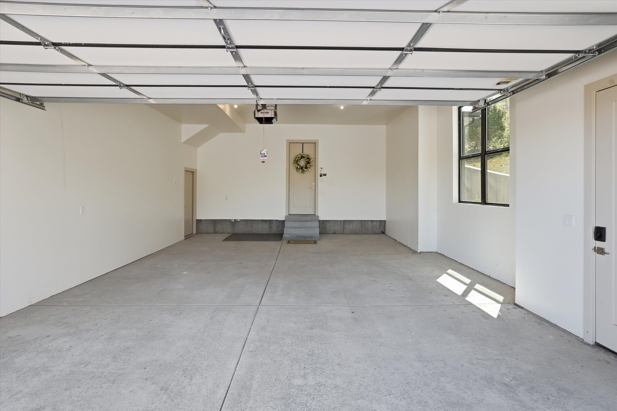 Spacious garage featuring a concrete floor, bright white walls, and an overhead garage door mechanism