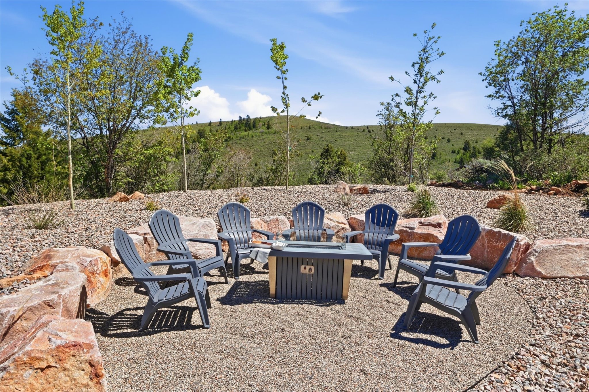 Outdoor gathering area featuring a central fire pit, surrounded by a gravel surface