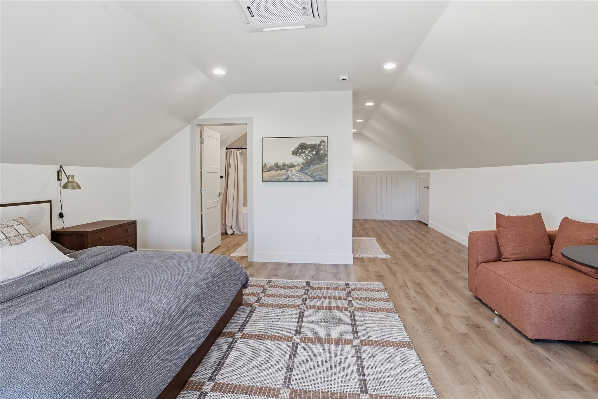 Spacious attic room with vaulted ceilings, recessed lighting, wood-finish flooring, and a mini-split HVAC system
