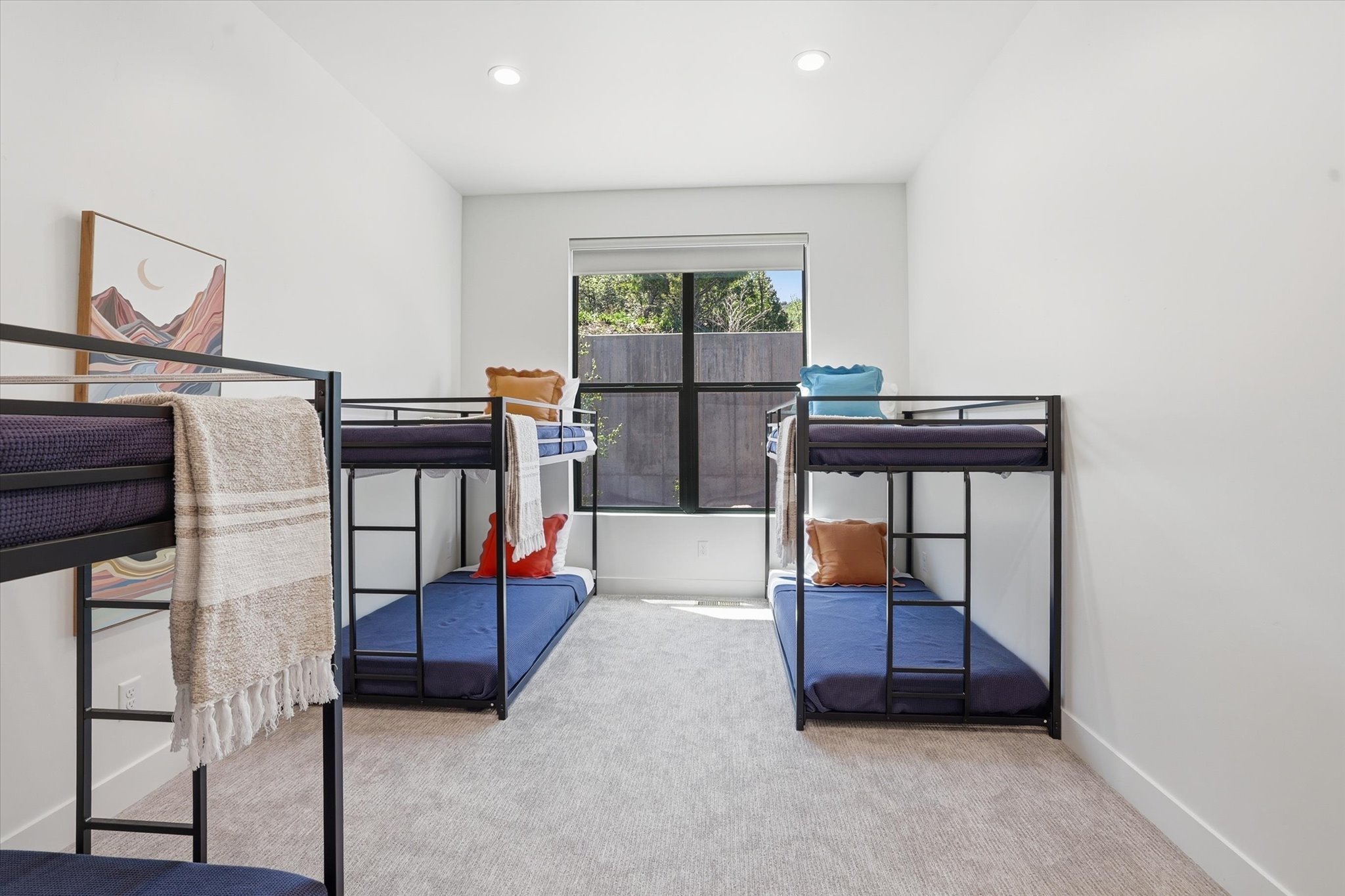 Spacious room featuring light-colored carpet flooring, recessed ceiling lights, and a large window with a dark frame