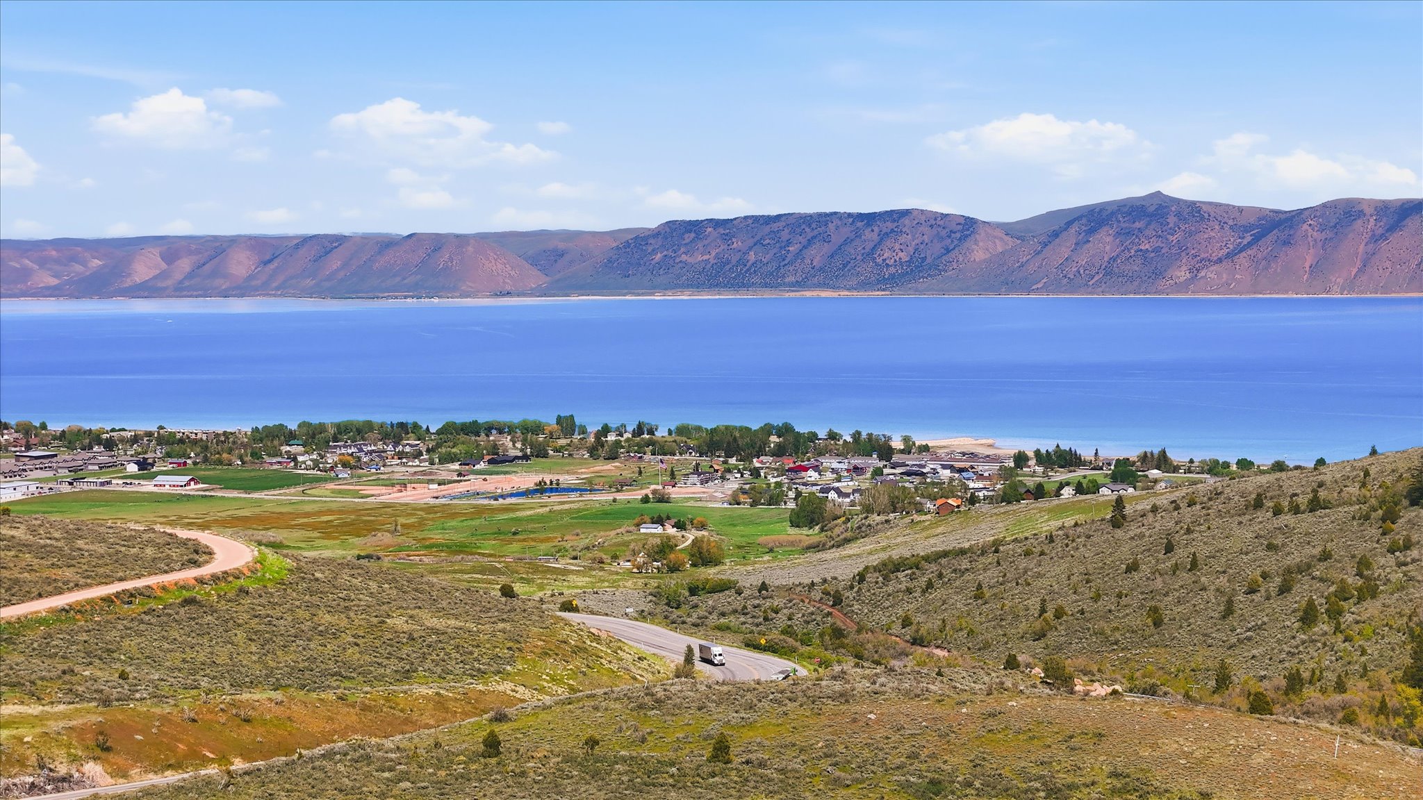 Expansive landscape featuring distant mountains, a large body of water, and a small town